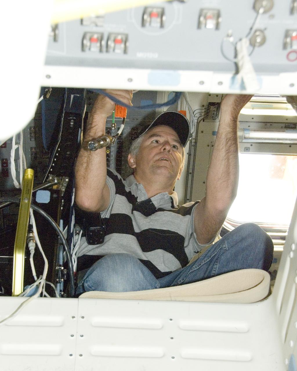 United Space Alliance technician Mark Shimei works inside Space Shuttle Endeavour's flight deck during deservicing operations at NASA Dryden following its landing at Edwards Air Force Base on Nov. 30, 2008.