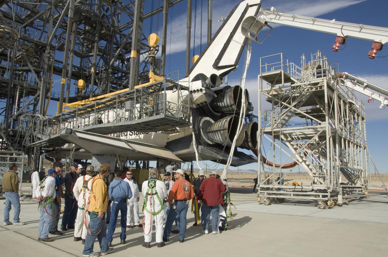 United Space Alliance technicians gather around the rear of Space Shuttle Endeavour for a safety briefing prior to moving the tail workstand around the shuttle's engines.