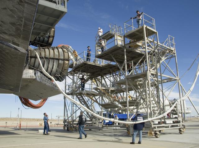 NASA image: echnicians monitor the positioning of a workstand as it is moved into place around the main engines of the shuttle Endeavour during deservicing at NASA DFRC