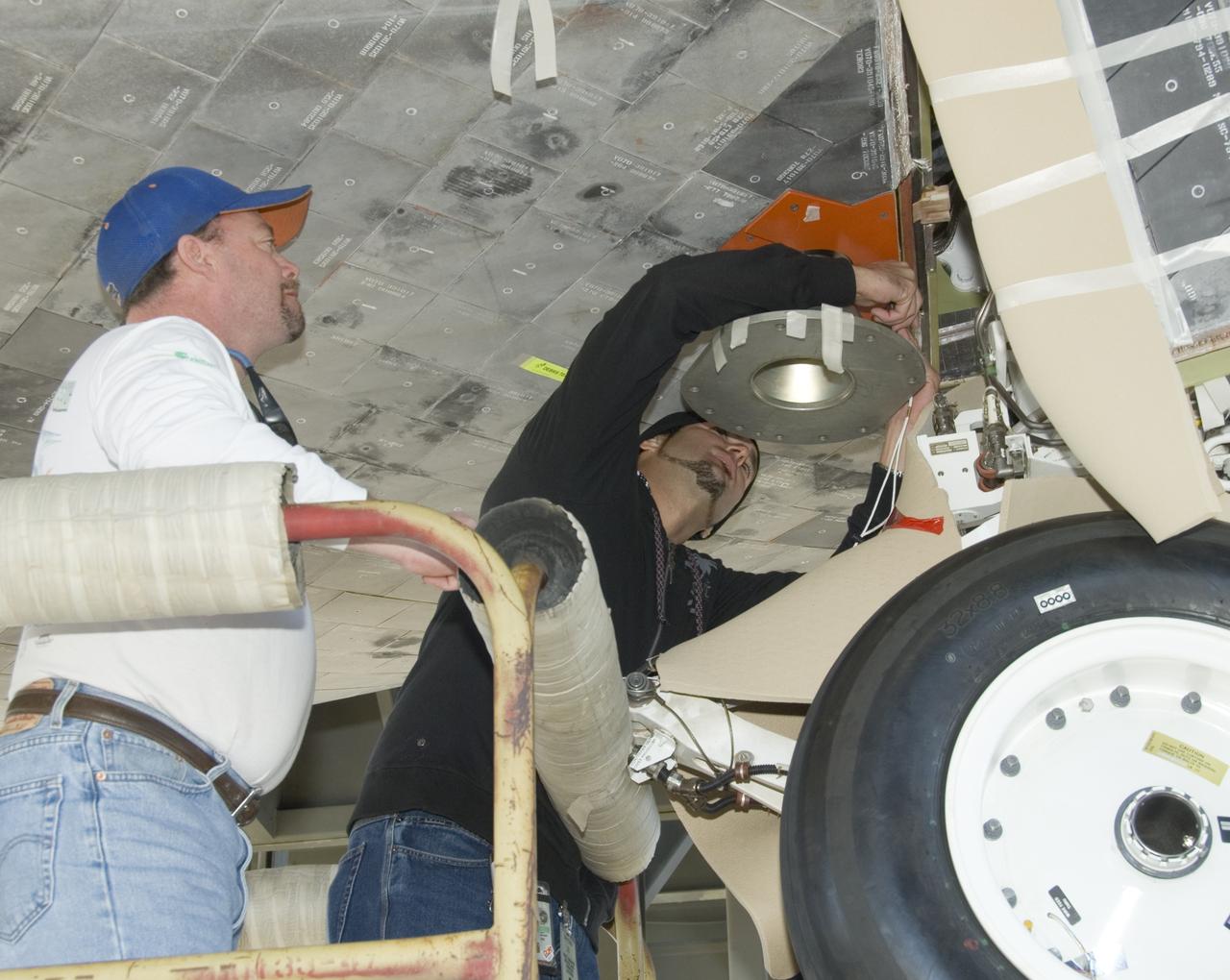 United Space Alliance employees Mark Burton and Russell Wazniak attach the forward mount fixture to Shuttle Endeavour for mounting the orbiter to the 747 Shuttle Carrier Aircraft.