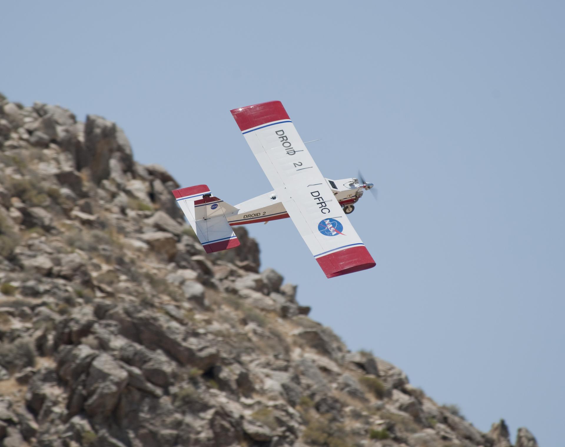 NASA’s Dryden Remotely Operated Integrated Drone (DROID), a small, remotely piloted research aircraft with a 10‑foot wingspan, makes a hard climbing right turn to avoid a steep rocky slope near NASA’s Armstrong Flight Research Center in Edwards, California, on Thursday, May 31, 2012. The flight tests demonstrated that a remotely piloted aircraft, equipped with a smartphone running collision-avoidance software connected to the aircraft’s autopilot, could automatically avoid terrain below.