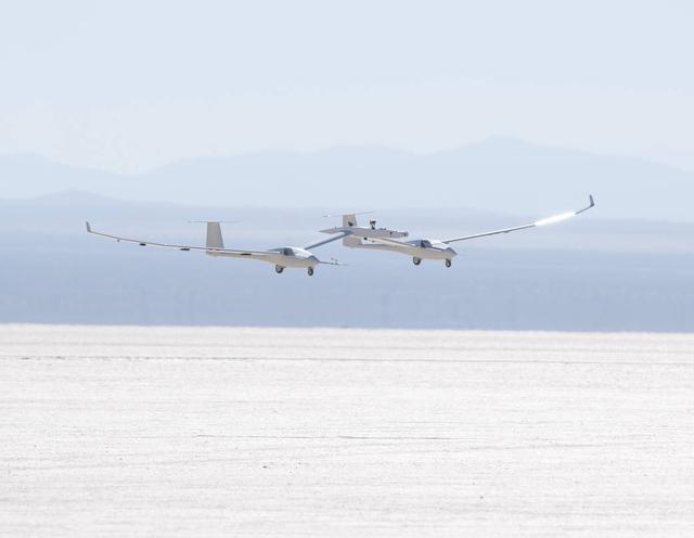 The one-third scale twin-fuselage towed glider glides in for landing on Rogers Dry Lake after its successful first test flight.