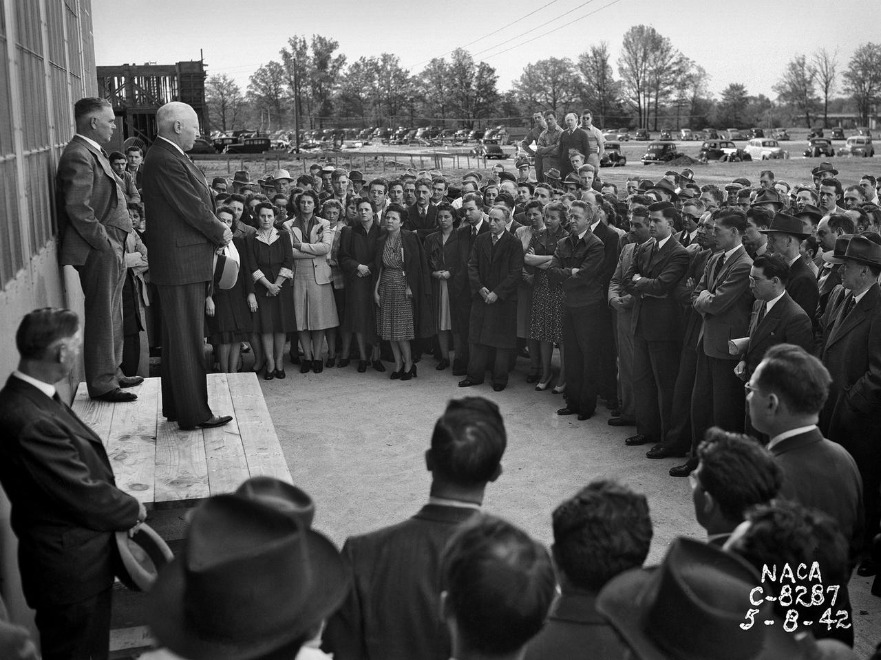 Construction Manager Raymond Sharp and the National Advisory Committee for Aeronautics (NACA) Director of Research George Lewis speak to employees during the May 8, 1942, Initiation of Research ceremony at the Aircraft Engine Research Laboratory. The event marked the first operation of a test facility at the new laboratory. The overall laboratory was still under construction, however, and behind schedule.       Lewis traveled from his office in Washington, DC every week to personally assess the progress. Drastic measures were undertaken to accelerate the lab’s construction schedule. The military provided special supplies, contractors were given new agreements and pressured to meet deadlines, and Congress approved additional funds. The effort paid off and much of the laboratory was operational in early 1943.   George Lewis managed the NACA’s aeronautical research for over 20 years. Lewis joined the NACA as Executive Officer in 1919, and was named Director of Aeronautical Research in 1924. In this role Lewis served as the liaison between the Executive Committee and the research laboratories. His most important accomplishment may have been the investigative tours of the research facilities in Germany in 1936 and 1939. The visits resulted in the NACA’s physical expansion and the broadening of the scope of its research. Lewis did not take a day of leave between the Pearl Harbor attack and the Armistice. He began suffering health problems in 1945 and was forced to retire two years later. The Aircraft Engine Research Laboratory was renamed the NACA Lewis Flight Propulsion Laboratory in September 1948.