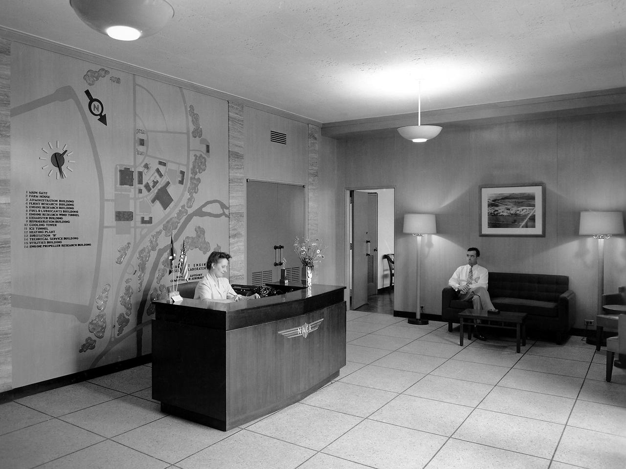 Receptionist Mary Louise Gosney enjoys the new Administration Building at the NACA’s Aircraft Engine Research Laboratory. The Administration Building, which was located near the front entrance to the laboratory, opened in December 1942. The staff, which had spent the previous year working in temporary offices inside the hangar, quickly occupied the new building. Lab director Raymond Sharp, the upper management team, and administrative staff had offices in the Administration Building. The structure also contained the lab’s library and auditorium. Gosney was a Chicago native who started at the lab in November 1941. Gosney’s services included welcoming visitors, arranging tours, and arranging interviews with staff members. Gosney’s “Lobby Lines” column in the lab’s newsletter Wing Tips noted the coming and goings of notable visitors and staff members. In addition to her role as receptionist, Gosney also served as the clearance officer. She would later head the entire Administrative Services Division.