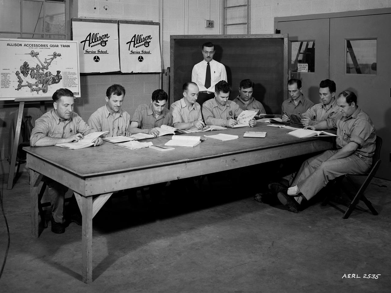 The Allison Engine Company's A.G. Covell instructs mechanics from various divisions at the National Advisory Committee for Aeronautics (NACA) Aircraft Engine Research Laboratory on the operation of the Allison Basic Engine. The military had asked that the laboratory undertake an extensive program to improve the performance of the Allison V–1710 engine. The V–1710 was the only liquid-cooled engine used during World War II, and the military counted on it to power several types of fighter aircraft.       The NACA instituted an Apprentice Program during the war to educate future mechanics, technicians, and electricians. The program was suspended for a number of years due to the increasing rates of military service by its participants. The laboratory continued its in-house education during the war, however, by offering a number of classes to its employees and lectures for the research staff. The classes and lectures were usually taught by fellow members of the staff, but occasionally external experts were brought in.    The students in the Allison class in the Engine Research Building were taught how to completely disassemble and reassemble the engine components and systems. From left to right are Don Vining, Ed Cudlin, Gus DiNovo, George Larsen, Charles Diggs, Martin Lipes, Harley Roberts, Martin Berwaldt and John Dempsey. A.G. Covell is standing.