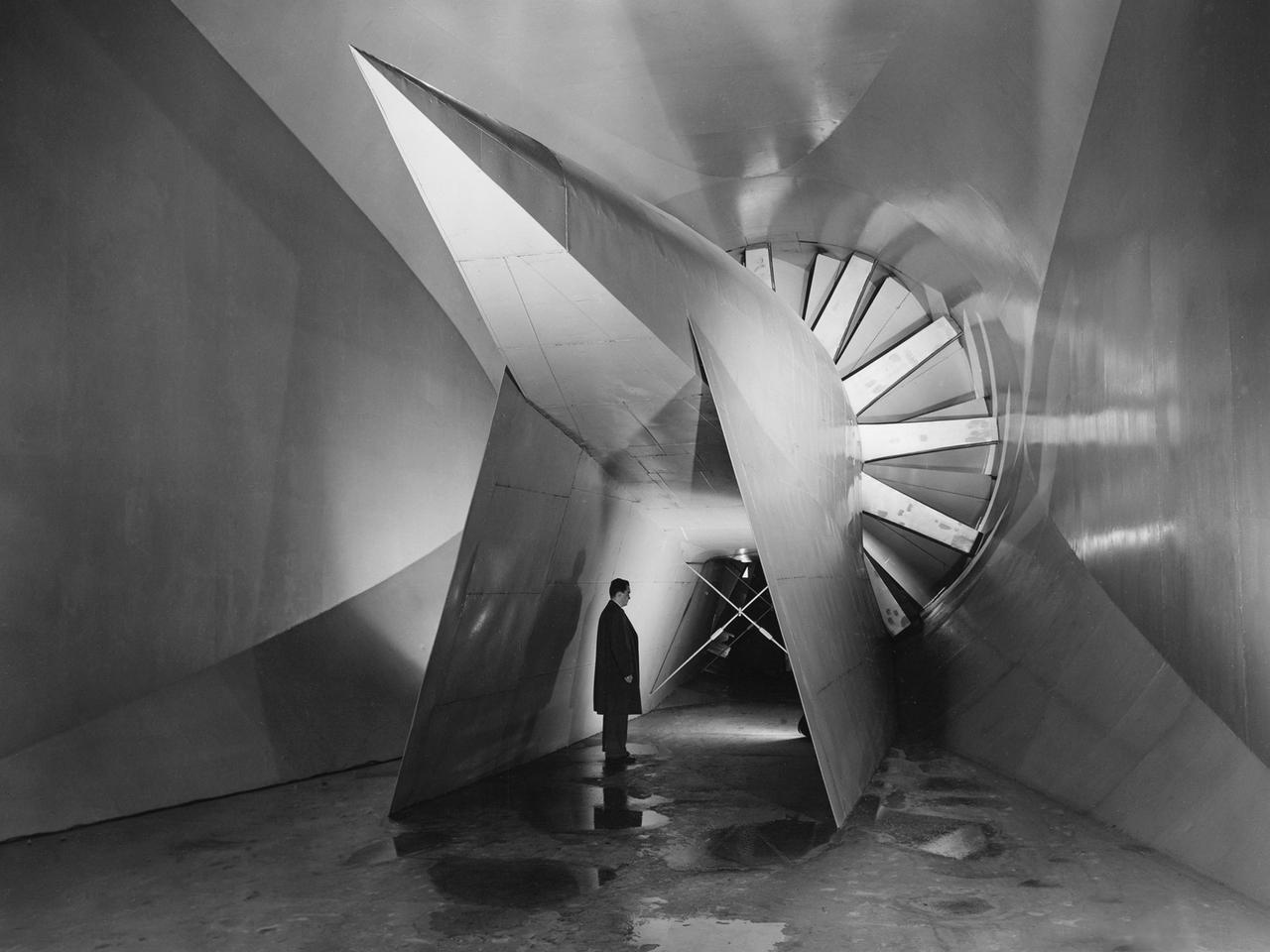 View of the drive fan for the Icing Research Tunnel at the National Advisory Committee for Aeronautics (NACA) Aircraft Engine Research Laboratory in Cleveland, Ohio. The tunnel was built in the early 1940s to study the formation of ice on aircraft surfaces and methods of preventing or eradicating that ice. Ice buildup adds extra weight, effects aerodynamics, and sometimes blocks airflow through engines.     The original 4100-horsepower induction motor was coupled directly to the 24-foot-diameter fan. The 12 wooden fan blades were protected on their leading edge by a neoprene boot. The system could create air speeds up to 300 miles per hour through the tunnel’s 6- by 9-foot test section. The large tail faring extending from the center of the fan is used to guide the airflow down the tunnel in a uniform way. A new 5000-horsepower motor was installed in 1987, and the original fan blades were replaced in 1993.