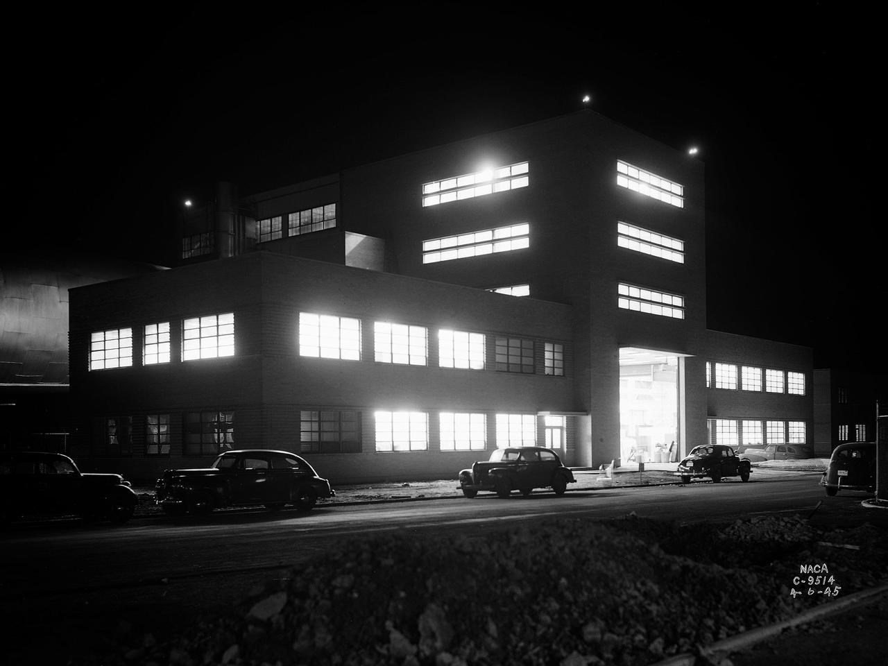 The Altitude Wind Tunnel (AWT) during one of its overnight runs at the National Advisory Committee for Aeronautics (NACA) Aircraft Engine Research Laboratory in Cleveland, Ohio. The AWT was run during night hours so that its massive power loads were handled when regional electric demands were lowest. At the time the AWT was among the most complex wind tunnels ever designed. In order to simulate conditions at high altitudes, NACA engineers designed innovative new systems that required tremendous amounts of electricity. The NACA had an agreement with the local electric company that it would run its larger facilities overnight when local demand was at its lowest. In return the utility discounted its rates for the NACA during those hours.       The AWT could produce wind speeds up to 500 miles per hour through its 20-foot-diameter test section at the standard operating altitude of 30,000 feet. The airflow was created by a large fan that was driven by an 18,000-horsepower General Electric induction motor. The altitude simulation was accomplished by large exhauster and refrigeration systems. The cold temperatures were created by 14 Carrier compressors and the thin atmosphere by four 1750-horsepower exhausters.    The first and second shifts usually set up and broke down the test articles, while the third shift ran the actual tests. Engineers would often have to work all day, then operate the tunnel overnight, and analyze the data the next day. The night crew usually briefed the dayshift on the tests during morning staff meetings.