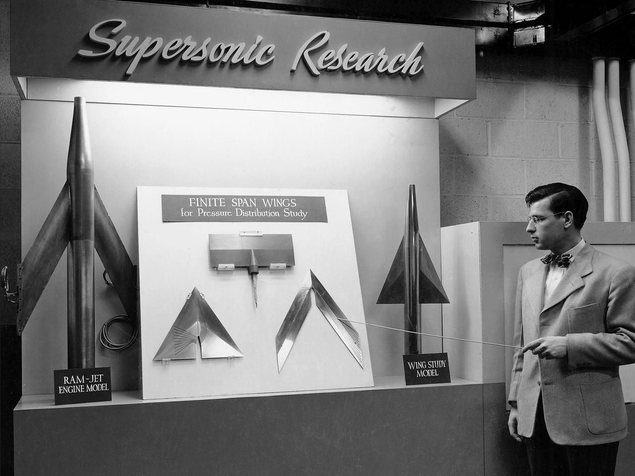 On March 22, 1946, 250 members of the Institute of Aeronautical Science toured the NACA’s Aircraft Engine Research Laboratory. NACA Chairman Jerome Hunsaker and Secretary John Victory were on hand to brief the attendees in the Administration Building before the visited the lab’s test facilities. At each of the twelve stops, researchers provided brief presentations on their work. Topics included axial flow combustors, materials for turbine blades, engine cooling, icing prevention, and supersonic flight.    The laboratory reorganized itself in October 1945 as World War II came to an end to address newly emerging technologies such as the jet engine, rockets, and high-speed flight. While design work began on what would eventually become the 8- by 6-Foot Supersonic Wind Tunnel, NACA Lewis quickly built several small supersonic tunnels. These small facilities utilized the Altitude Wind Tunnel’s massive air handling equipment to generate high-speed airflow.    The display seen in this photograph was set up in the building that housed the first of these wind tunnels. Eventually the building would contain three small supersonic tunnels, referred to as the “stack tunnels” because of the vertical alignment. The two other tunnels were added to this structure in 1949 and 1951. The small tunnels were used until the early 1960s to study the aerodynamic characteristics of supersonic inlets and exits.