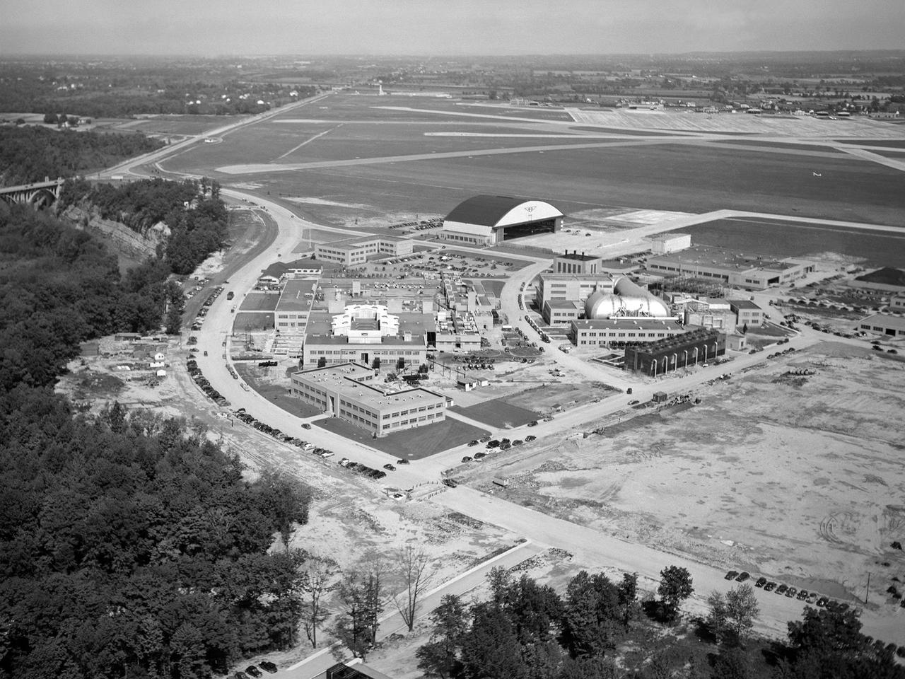 The National Advisory Committee for Aeronautics (NACA) Lewis Flight Propulsion Laboratory in Cleveland, Ohio as seen from the west in May 1946. The Cleveland Municipal Airport is located directly behind. The laboratory was built in the early 1940s to resolve problems associated with aircraft engines. The initial campus contained seven principal buildings: the Engine Research Building, hangar, Fuels and Lubricants Building, Administration Building, Engine Propeller Research Building, Altitude Wind Tunnel, and Icing Research Tunnel. These facilities and their associated support structures were located within an area occupying approximately one-third of the NACA’s property. After World War II ended, the NACA began adding new facilities to address different problems associated with the newer, more powerful engines and high speed flight. Between 1946 and 1955, four new world-class test facilities were built: the 8- by 6-Foot Supersonic Wind Tunnel, the Propulsion Systems Laboratory, the Rocket Engine Test Facility, and the 10- by 10-Foot Supersonic Wind Tunnel. These large facilities occupied the remainder of the NACA’s semicircular property. The Lewis laboratory expanded again in the late 1950s and early 1960s as the space program commenced. Lewis purchased additional land in areas adjacent to the original laboratory and acquired a large 9000-acre site located 60 miles to the west in Sandusky, Ohio. The new site became known as Plum Brook Station.