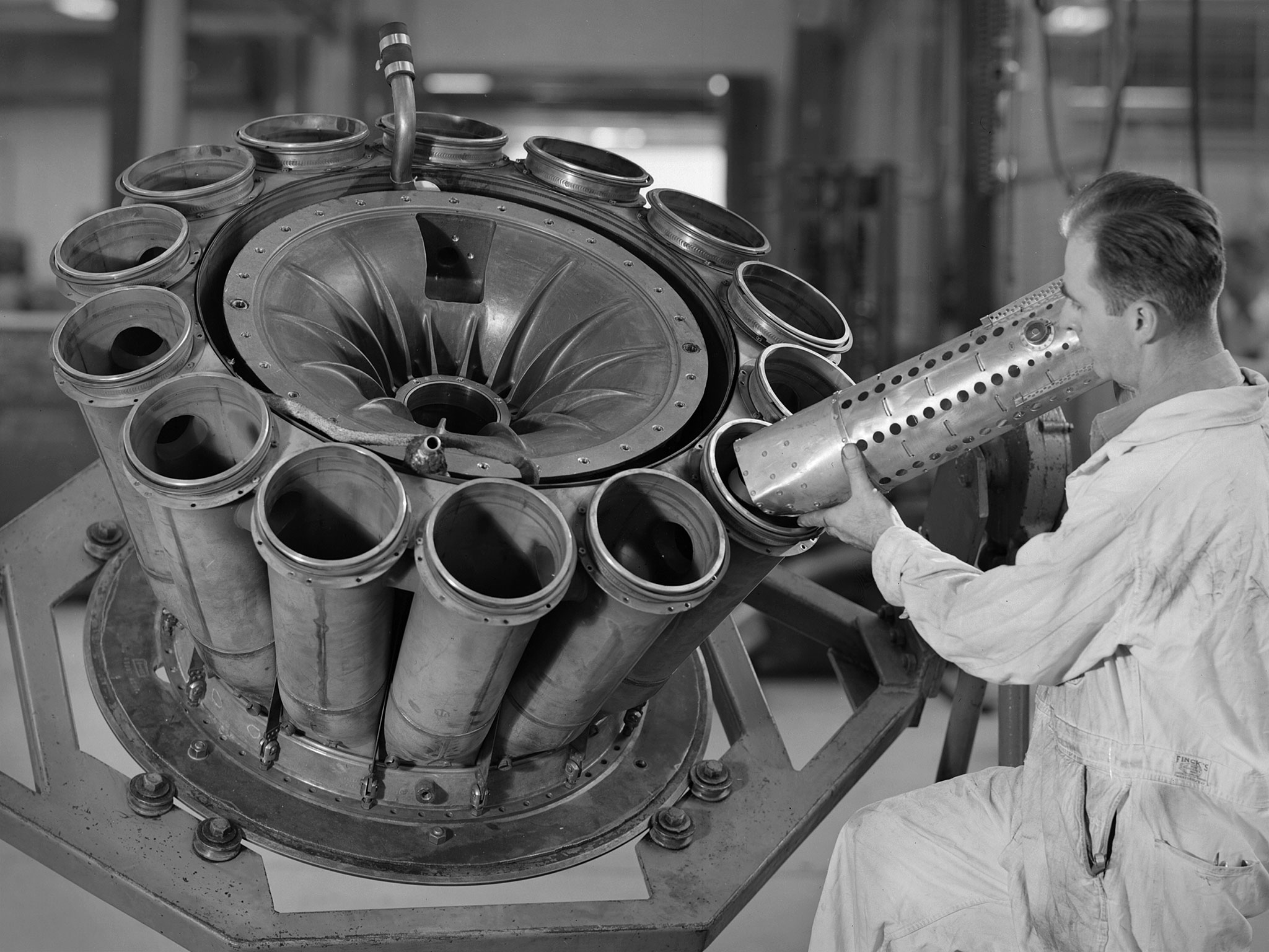 A man looks at a cylinder that is seated in a tube that is part of the General Electric I-40 turbojet