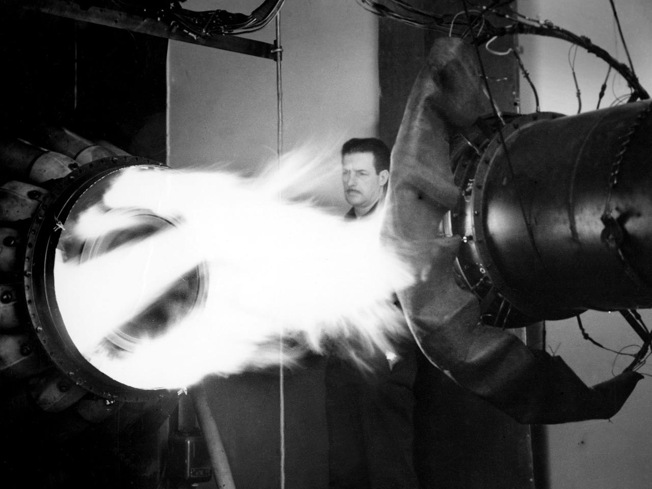 A mechanic watches the firing of a General Electric I-40 turbojet at the National Advisory Committee for Aeronautics (NACA) Lewis Flight Propulsion Laboratory. The military selected General Electric’s West Lynn facility in 1941 to secretly replicate the centrifugal turbojet engine designed by British engineer Frank Whittle. General Electric’s first attempt, the I-A, was fraught with problems. The design was improved somewhat with the subsequent I-16 engine.  It was not until the engine's next reincarnation as the I-40 in 1943 that General Electric’s efforts paid off. The 4000-pound thrust I-40 was incorporated into the Lockheed Shooting Star airframe and successfully flown in June 1944. The Shooting Star became the US’s first successful jet aircraft and the first US aircraft to reach 500 miles per hour.    NACA Lewis studied all of General Electric’s centrifugal turbojet models during the 1940s. In 1945 the entire Shooting Star aircraft was investigated in the Altitude Wind Tunnel. Engine compressor performance and augmentation by water injection; comparison of different fuel blends in a single combustor; and air-cooled rotors were studied.   The mechanic in this photograph watches the firing of a full-scale I-40 in the Jet Propulsion Static Laboratory. The facility was quickly built in 1943 specifically in order to test the early General Electric turbojets. The I-A was secretly analyzed in the facility during the fall of 1943.