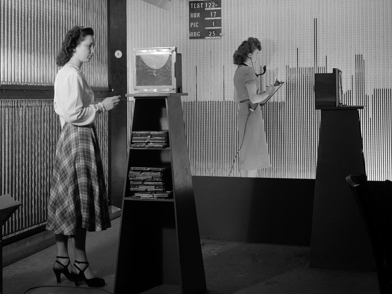 Female computers at the National Advisory Committee for Aeronautics (NACA) Lewis Flight Propulsion Laboratory copy pressure readings from rows of manometers below the 18- by 18-inch Supersonic Wind Tunnel. The computers obtained test data from the manometers and other instruments, made the initial computations, and plotted the information graphically. Based on these computations, the researchers planned their next test or summarized their findings in a report.    Manometers were mercury-filled glass tubes that were used to indicate different pressure levels from inside the test facility or from the test article. Manometers look and function very similarly to thermometers. Dozens of pressure sensing instruments were installed for each test. Each was connected to a manometer tube located inside the control room. The mercury inside the manometer rose and fell with the pressure levels. The dark mercury can be seen in this photograph at different levels within the tubes. Since this activity was dynamic, it was necessary to note the levels at given points during the test. This was done using both computer notations and photography.