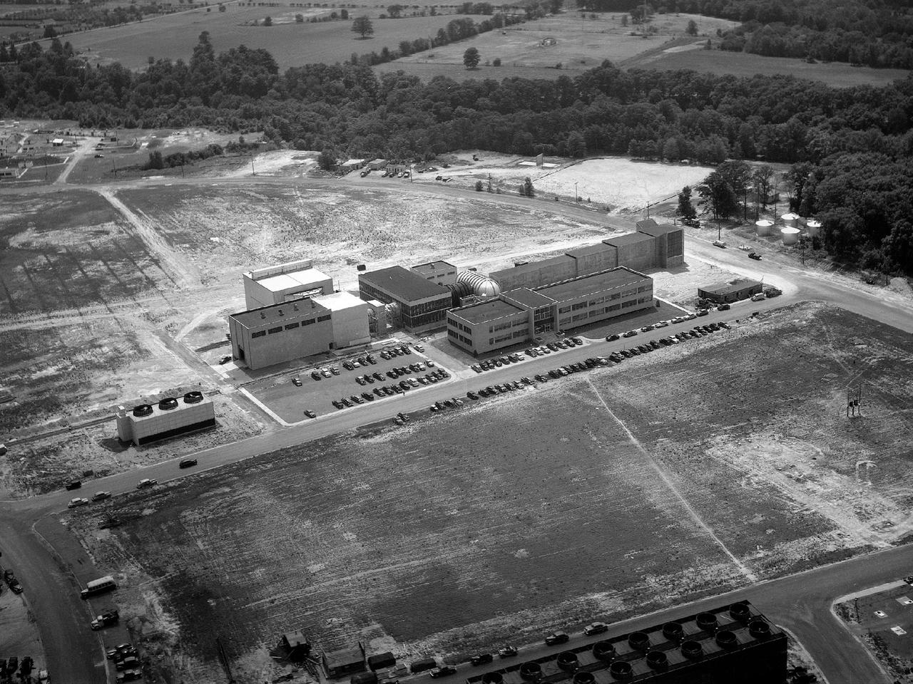 Aerial view of the 8- by 6-Foot Supersonic Wind Tunnel in its original configuration at the National Advisory Committee for Aeronautics (NACA) Lewis Flight Propulsion Laboratory. The 8- by 6 was the laboratory’s first large supersonic wind tunnel. It was also the NACA’s most powerful supersonic tunnel, and its first facility capable of running an engine at supersonic speeds. The 8- by 6-foot tunnel has been used to study inlets and exit nozzles, fuel injectors, flameholders, exit nozzles, and controls on ramjet and turbojet propulsion systems.    The 8- by 6 was originally an open-throat and non-return tunnel. This meant that the supersonic air flow was blown through the test section and out the other end into the atmosphere. In this photograph, the three drive motors in the structure at the left supplied power to the seven-stage axial-flow compressor in the light-colored structure. The air flow passed through flexible walls which were bent to create the desired speed. The test article was located in the 8- by 6-foot stainless steel test section located inside the steel pressure chamber at the center of this photograph. The tunnel dimensions were then gradually increased to slow the air flow before it exited into the atmosphere. The large two-story building in front of the tunnel was used as office space for the researchers.