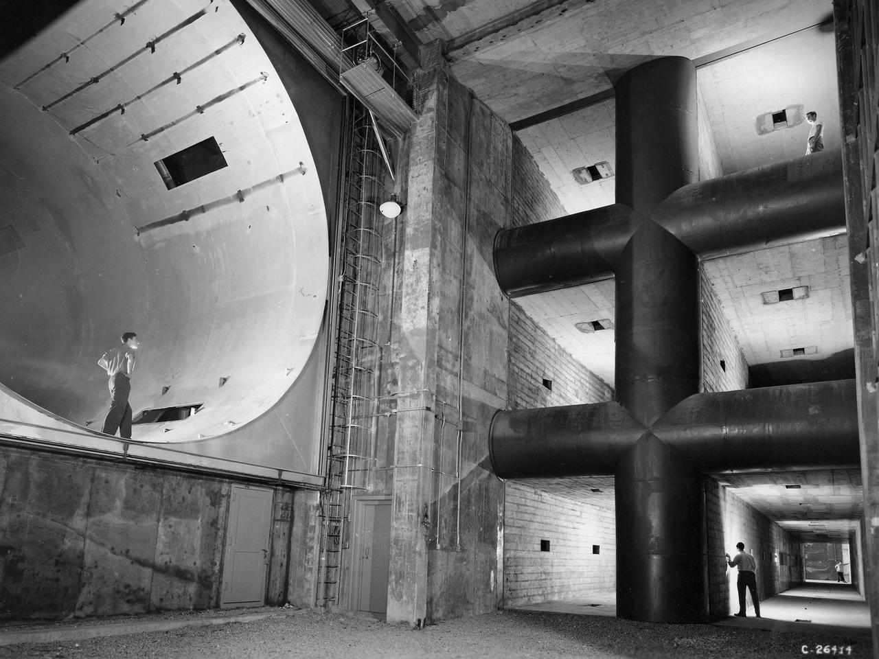 The 8- by 6-Foot Supersonic Wind Tunnel at the National Advisory Committee for Aeronautics (NACA) Lewis Flight Propulsion Laboratory was the largest supersonic wind tunnel in the nation at the time and the only one able to test full-scale engines at supersonic speeds. The 8- by 6 was designed as a non-return and open-throat tunnel. A large compressor created the air flow at one end of the tunnel, squeezed the flow to increase its velocity just before the test section, then reduced the velocity, and expelled it into the atmosphere at the other end of the tunnel.     This design worked well for initial aerodynamic testing, but the local community was literally rattled by the noise and vibrations when researchers began running engines in the test section in January 1950. The NACA’s most modern wind tunnel was referred to as “an 87,000-horsepower bugle aimed at the heart of Cleveland.” NACA Lewis responded to the complaints by adding an acoustic housing at the end of the tunnel to dampen the noise. The structure included resonator chambers and a reinforced concrete muffler structure. Modifications continued over the years. A return leg was added, and a second test section, 9 -by 15-foot, was incorporated in the return leg in the 1960s.    Since its initial operation in 1948, the 8- by 6-foot tunnel has been aggressively used to support the nation's aeronautics and space programs for the military, industry, and academia.