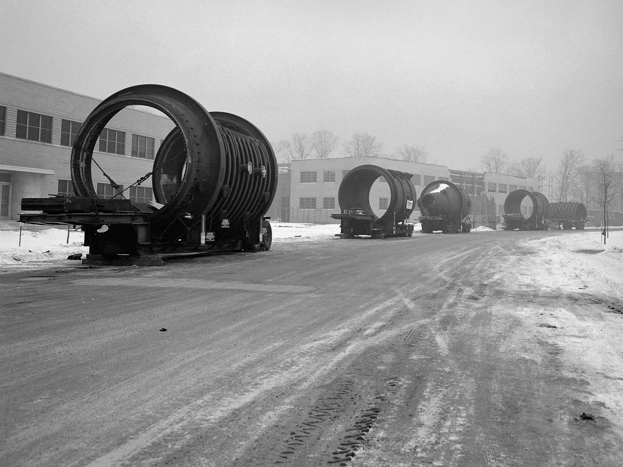 Huge cylinders are lined up along a road at the Lewis Flight Propulsion Laboratory