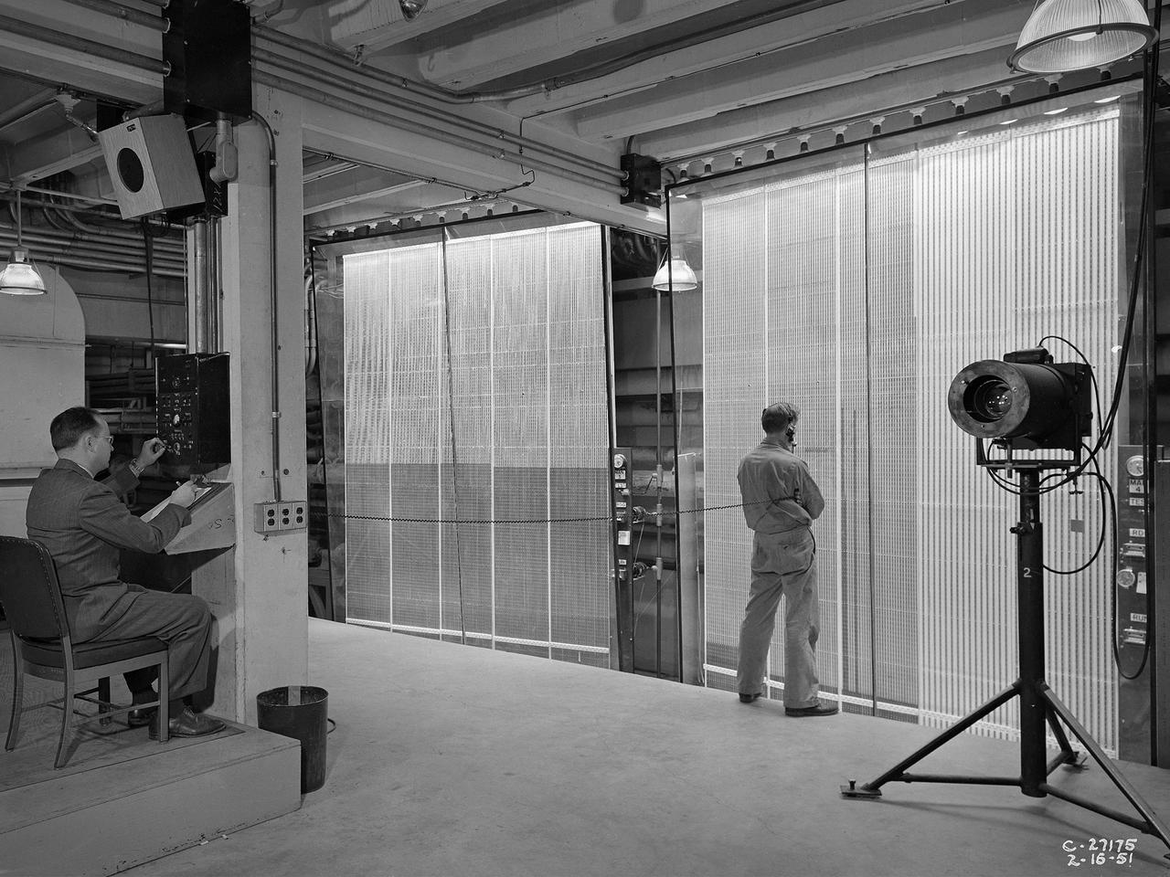 Analysts at the National Advisory Committee for Aeronautics (NACA) Lewis Flight Propulsion Laboratory take data readings from rows of manometers in the basement of the 8- by 6-Foot Supersonic Wind Tunnel. Manometers were mercury-filled glass tubes that indicated different pressure levels in the test section. Manometers look and function very similarly to thermometers. Pressure sensing instruments were installed on the test article inside the wind tunnel or other test facility. Each test could have dozens of such instruments installed and connected to a remotely located manometer tube. The mercury inside the manometer rose and fell with the pressure levels. The dark mercury can be seen at different levels within the tubes.    Since the pressure readings were dynamic, it was necessary to note the levels at given points during the test. This was done using both female computers and photography. A camera is seen on a stand to the right in this photograph.