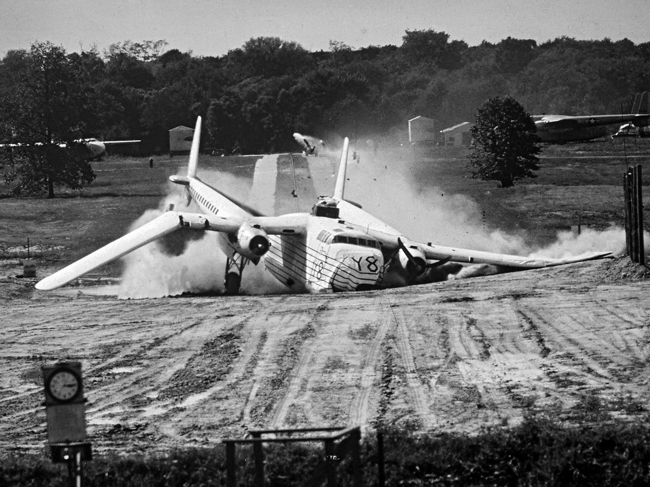 A Fairchild C-82 Packet is purposely destroyed by researchers at the National Advisory Committee for Aeronautics (NACA) Lewis Flight Propulsion Laboratory. In response to an escalating number of transport aircraft crashes in the mid-1940s, the NACA researchers undertook a decade-long investigation into a number of issues surrounding low-altitude aircraft crashes. The tests were conducted at the Ravenna Arsenal, approximately 60 miles south of the Lewis laboratory in Cleveland, Ohio.   The aircraft were excess military transports from World War II.  The aircraft was guided down the runway at speeds of 80 to 105 miles per hour. It came into contact with poles which tore open the 1500-gallon fuel tanks in the wings before reaching the barriers at the end of the runway. Fuel poured from the tanks and supply lines, resulting in the spread of both liquid fuel and a large cloud of spray. Solomon Weiss developed a method of dying the fuel red to improve its visibility during the crashes. This red fuel cloud trailed slightly behind the skidding aircraft, then rushed forward when the aircraft stopped.   The nine-crash initial phase of testing used Lockheed C-56 Lodestar and C-82 transport aircraft to identify potential ignition sources and analyze the spread of flammable materials. The researchers were able to identify different classes of ignition sources, fuel disbursement patterns, the time when a particular ignition source might appear, rate of the fire spread, cabin survival times, and deceleration rates.