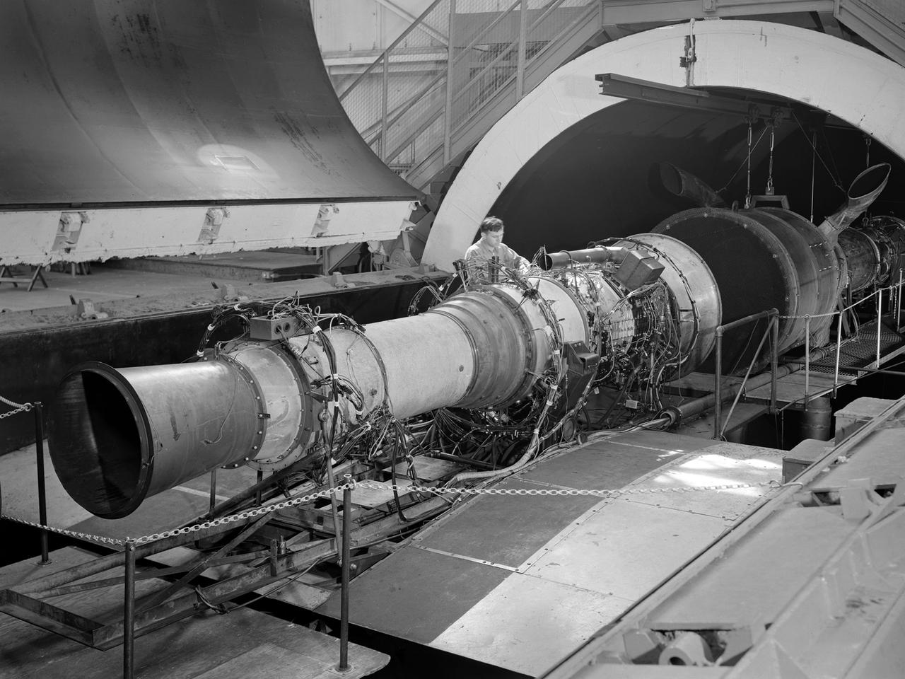 A Rolls Royce Avon RA-14 engine was tested in the Altitude Wind Tunnel at the National Advisory Committee for Aeronautics’ (NACA) Lewis Flight Propulsion Laboratory. The Avon RA-14 engine was a 16-stage axial-flow compressor turbojet capable of producing 9,500 pounds of thrust. The Avon replaced Rolls Royce’s successful Nene engine in 1950 and remained in service until 1974. It was one of several British engines studied in the tunnel during the 1950s.    The Altitude Wind Tunnel went through a series of modifications in 1951 to increase its capabilities. An annex was attached to the Exhauster Building to house three new Ingersoll-Rand compressors. The wooden blades on the tunnel’s 31-foot diameter fan were replaced, a pump house and exhaust cooler were constructed underneath the tunnel, and two new cells were added to the cooling tower. The modified wind tunnel continued to analyze jet engines in the 1950s, although the engines, like the RA-14 seen here, were much more powerful than those studied several years before.    Lewis researchers studied the RA-14 turbojet engine in the Altitude Wind Tunnel for 11 months in 1956. The engine was mounted on a stand capable of gauging engine thrust, and the tunnel’s air was ducted to the engine through a venturi and bellmouth inlet, seen in this photograph. The initial studies established the engine’s performance characteristics with a fixed-area nozzle and its acceleration characteristics. The researchers also used the tunnel to investigate windmilling of the compressor blades, restarting at high altitudes, and the engine’s performance limits at altitude.