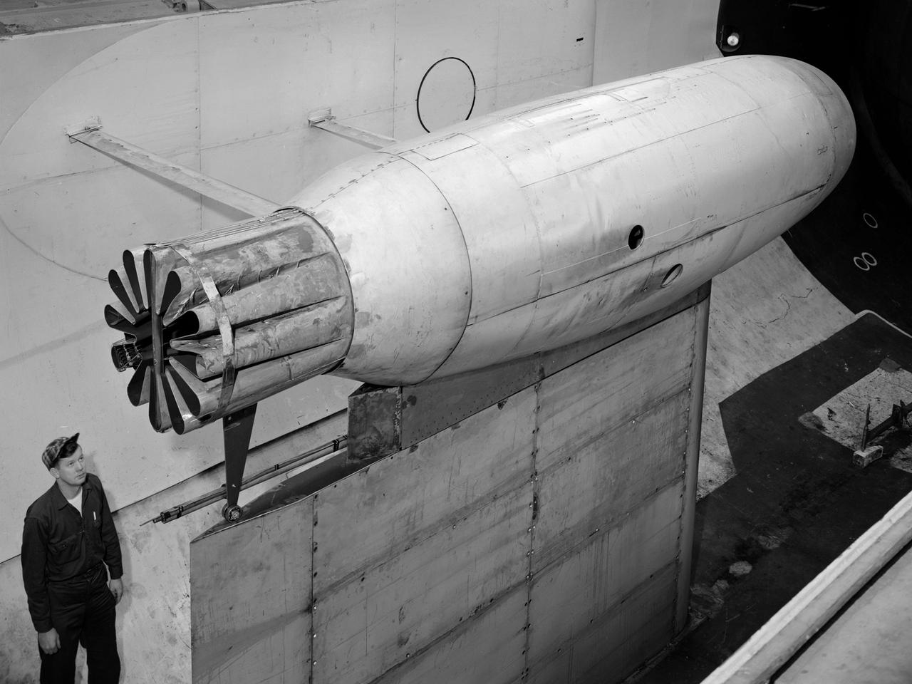 A Pratt and Whitney J57 engine is tested with a Greatex No.1 nozzle in the Altitude Wind Tunnel at the National Advisory Committee for Aeronautics (NACA) Lewis Flight Propulsion Laboratory. At the time the aircraft industry was preparing to introduce jet airliners to the nation’s airways. The noise produced by the large jet engines, however, posed a considerable problem for communities near airports. The NACA had formed a Special Subcommittee on Aircraft Noise to coordinate research on the issue. Preliminary tests showed that the source of the loudest noise was not the engine itself, but the mixing of the engine’s exhaust with the surrounding air in the atmosphere. The pressures resulting from this turbulence produced sound waves. Lewis researchers undertook a variety of noise-reduction studies involving engine design, throttling procedures, and noise suppressors. One of their first efforts focused on new types of nozzles to mix the exhaust with the surrounding air. The nozzles had a variety of shapes designed to slow down exhaust velocity before it combined with the air and thus decrease the noise. From January to May 1957 a Pratt and Whitney J57 engine was equipped with various shaped nozzles, as seen in this photograph, and run in simulated flight conditions in the Altitude Wind Tunnel. A number of nozzle configurations, including several multi-exit “organ pipe” designs, were created. It was found that the various nozzle types did reduce the noise levels, but they also reduced the aircraft’s thrust.