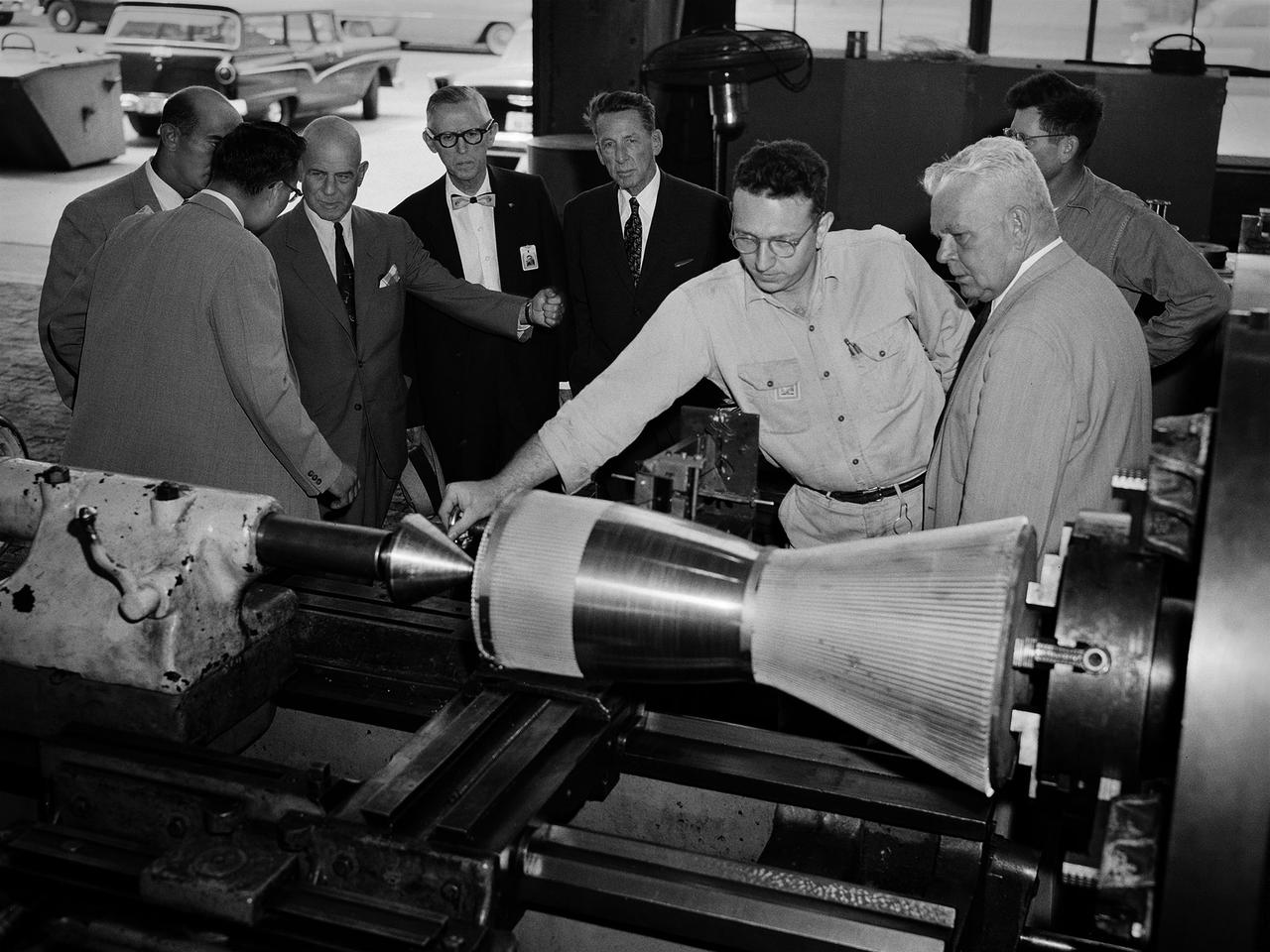 National Advisory Committee for Aeronautics (NACA) Chairman James Doolittle and Thompson Products Chairman of the Board Frederick Crawford receive a tour of the Lewis Flight Propulsion Laboratory during the last few months of the NACA. Lewis mechanic Leonard Tesar demonstrates the machining of a 20,000-pound thrust rocket engine for the group in the Fabrication Shop. From left to right, Associate Director Eugene Manganiello, researcher Edward Baehr, Doolittle, NACA Executive Secretary John Victory, Crawford, Tesar, Lewis Director Raymond Sharp, and mechanic Curtis Strawn.                         Doolittle began his career as a test pilot and air racer. In 1942 he famously flew a B-25 Mitchell on a daring raid over Tokyo. Doolittle also worked with the aviation industry on the development of aircraft fuels and instrumentation. After the war he served as vice president of Shell Oil and as a key government advisor. In this capacity he also served on the NACA’s Executive Committee for a number of years and served as its Chairman in 1957 and 1958.    Tesar was a supervisor at the Sheet Metal Shop in the Fabrication Building. He joined the laboratory in 1948 and enrolled in their Apprentice Program. He graduated from the school three years later as an aviation metalsmith. The Fabrication Branch created a wide variety of hardware for the laboratory’s research projects. Requests from research divisions ranged from sheetmetal manufacturing for aircraft to fabrication of rocket engines. Tesar retired in 1982 after 37 years of service.