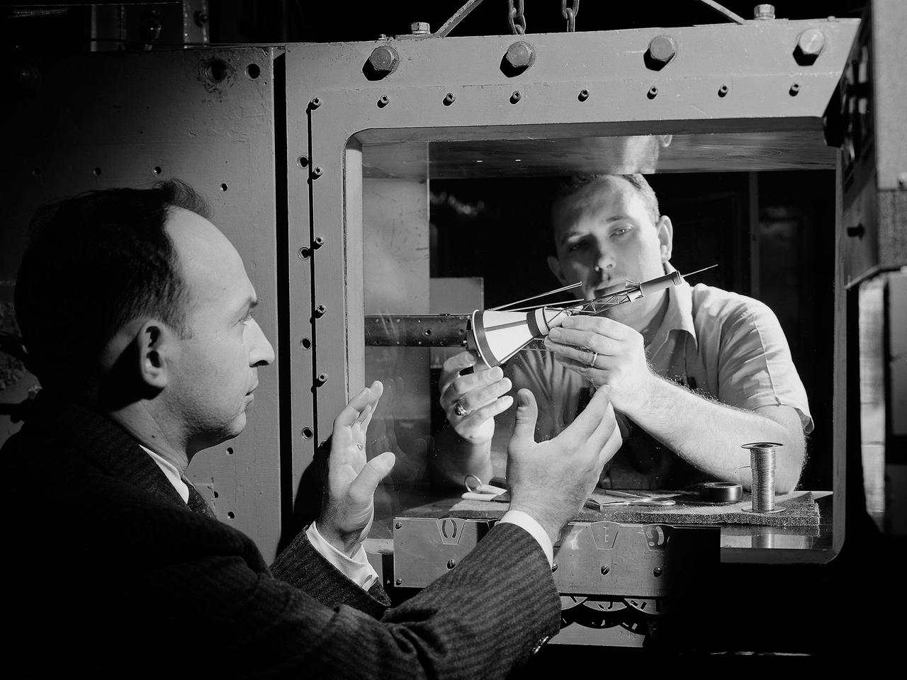 National Aeronautics and Space Administration (NASA) researchers install a small-scale model of the capsule for Project Mercury in the 1- by 1-Foot Supersonic Wind Tunnel at the Lewis Research Center. NASA Lewis conducted a variety of tests for Project Mercury, including retrorocket calibration, escape tower engine performance, and separation of the capsule from simulated Atlas and Redstone boosters. The test of this capsule and escape tower model in the 1- by 1-foot tunnel were run in January and February 1960.       The 1-by 1-Foot Supersonic Wind Tunnel had a 15-inch long test section, seen here, that was one foot wide and one foot high. The sides were made of glass to allow cameras to capture the supersonic air flow over the models. The tunnel could generate air flows from Mach 1.3 to 3.0. At the time, it was one of nine small supersonic wind tunnels at Lewis. These tunnels used the exhauster and compressor equipment of the larger facilities.    The 1- by 1 tunnel, which began operating in the early 1950s, was built inside a test cell in the expansive Engine Research Building. During the 1950s the 1- by 1 was used to study a variety of inlets, nozzles, and cones for missiles and scramjets. The Mercury capsule tests were among the last at the facility for many years. The tunnel was mothballed in 1960. The 1- by 1 was briefly restored in 1972, then brought back online for good in 1979. The facility has maintained a brisk operating schedule ever since.