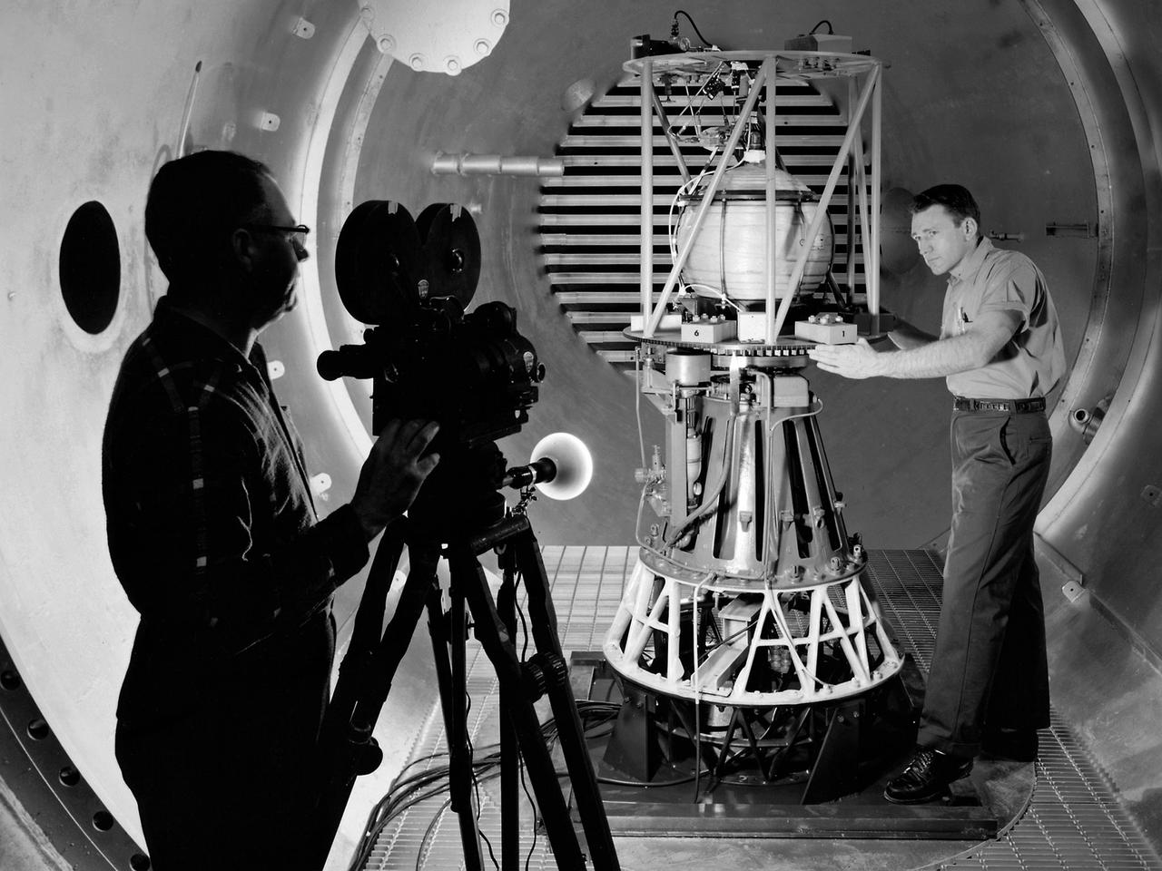 Mechanic Howard Wine inspects the setup of a spin isolator in Cell 2 of the Propulsion Systems Laboratory at the National Aeronautics and Space Administration (NASA) Lewis Research Center. Photographer Al Jecko filmed the proceedings. This test was unique in that the chamber’s altitude system was used, but not its inlet air flow. The test was in preparation for an upcoming launch of modified liquid hydrogen propellant tank on a sounding rocket. This Weightlessness Analysis Sounding Probe (WASP) was part of Lewis investigation into methods for controlling partially filled liquid hydrogen fuel tanks during flight. Second-stage rockets, the Centaur in particular, were designed to stop their engines and coast, then restart them when needed. During this coast period, the propellant often shifted inside the tank. This movement could throw the rocket off course or result in the sloshing of fuel away from the fuel pump. Wine was one of only three journeymen mechanics at Lewis when he was hired in January 1954. He spent his first decade in the Propulsion Systems Laboratory and was soon named a section head. Wine went on to serve as Assistant Division Chief and later served as an assistant to the director. Jecko joined the center in 1947 as a photographer and artist. He studied at the Cleveland School or Art and was known for his cartoon drawing. He worked at the center for 26 years.