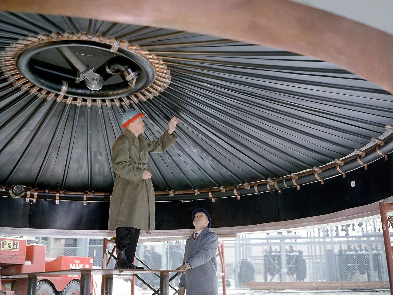 Engineers at the National Aeronautics and Space Administration (NASA) Lewis Research Center inspect the nitrogen baffle in the interior of the 22.5-foot diameter dome at the Space Power Chambers. In 1961 NASA Lewis management decided to convert the Altitude Wind Tunnel into two large test chambers and renamed the facility the Space Power Chambers. The conversion, which took over two years, included removing the tunnel’s drive fan, exhaust scoop, and turning vanes from the east end and inserting bulkheads to seal off the new chambers within the tunnel.     The eastern section of the tunnel became a vacuum chamber capable of simulating 100 miles altitude. In 1962 NASA management decided to use the new vacuum chamber exclusively to study the second-stage rocket. This required significant modifications to the new tank and extensive test equipment to create a space environment. The Lewis test engineers sought to subject the Centaur to long durations in conditions that would replicate those encountered during its missions in space.     The chamber was already capable of creating the vacuum of space, but the test engineers also wanted to simulate the cryogenic temperatures and solar radiation found in space. Six panels of 500-watt tungsten-iodine lamps were arranged around the Centaur to simulate the effect of the Sun’s heat. A large copper cold wall with its interior coated with heat-absorbing black paint was created specifically for these tests and assembled around the Centaur. The 42-foot-high wall had vertical ribs filled with liquid nitrogen which produced the low temperatures.