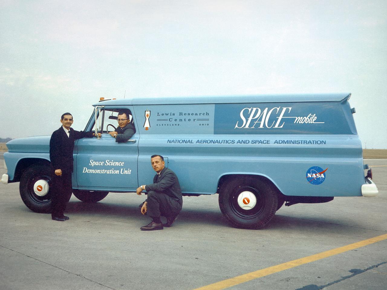 Members of Lewis’ Educational Services Office pose with one of the center’s Spacemobile space science demonstration units. Unlike its predecessor, the NACA, the new NASA space agency considered public outreach one of its core tenets. The early astronauts were lionized and new technologies touted. Lewis, which had previously been a closed laboratory, began hosting open houses and elaborate space fairs in the early 1960s.     In addition, the center initiated educational programs that worked with local schools and a robust speaker’s bureau that explained NASA activities to the community. One aspect of these efforts was the Spacemobile Program. These vehicles included a delegated speaker, exhibits, models, and other resources. The Spacemobiles, which made forays across the Midwest, were extremely active throughout the 1960s.