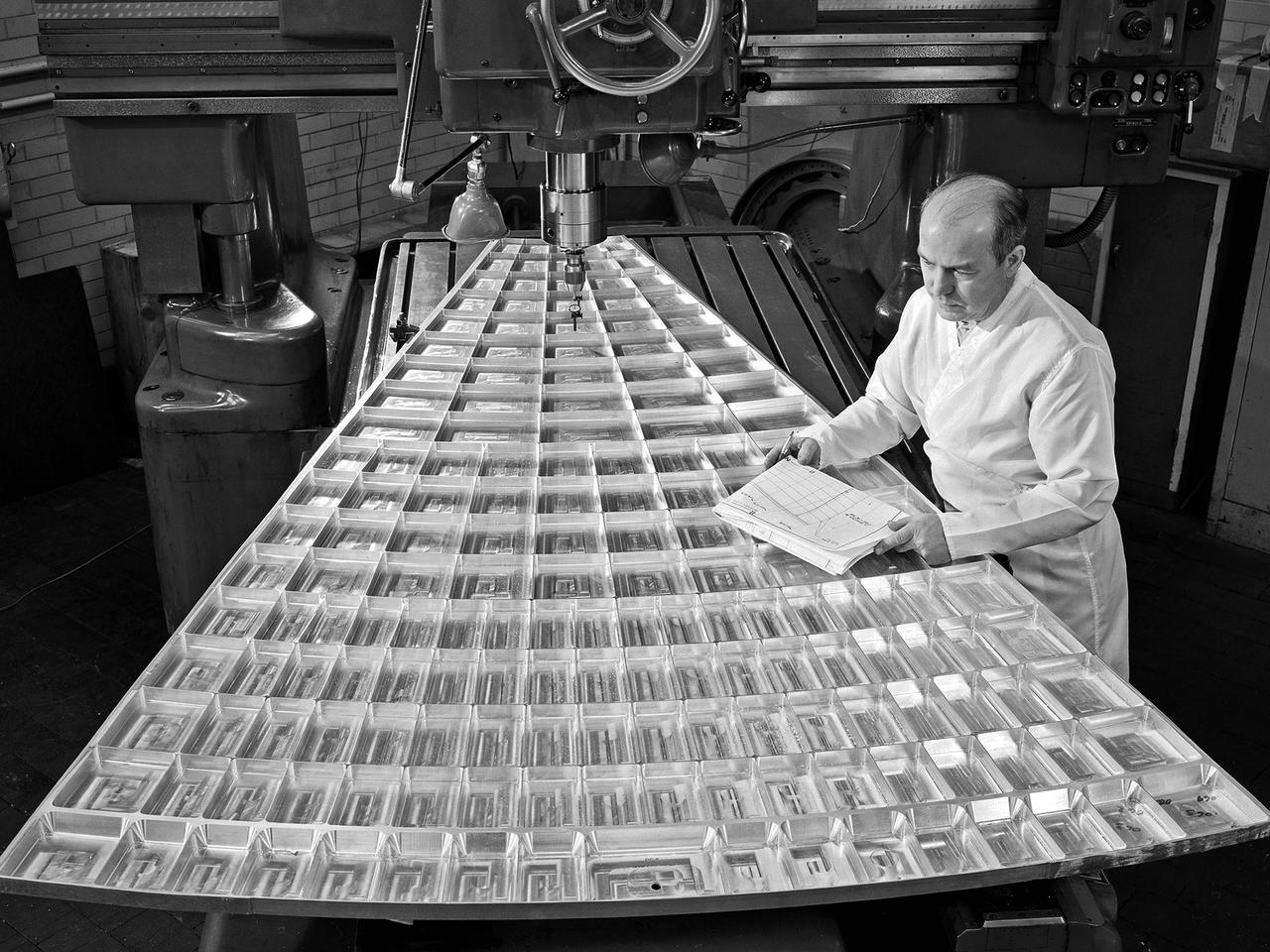 Daniel Bernatowicz, Chief of the Advanced Power Systems Branch at the National Aeronautics and Space Administration (NASA) Lewis Research Center, examines a 20-foot section of a solar mirror being fabricated in the Jig Bore Room of the Technical Services Building. NASA Lewis was conducting a wide-ranging effort to explore methods of generating electrical power for spacecraft. One method employed a large parabolic mirror to concentrate the sun’s energy. The mirror had to remain rigid and withstand micrometeoroids, but remain light and compact enough to be easily launched. In 1963 Bernatowicz and his researchers undertook a program to design a solar mirror to work with the Brayton cycle system on a space station. The mirror in this photograph was prepared for a conference on Advanced Technology in Space Power Systems held at Lewis in late August 1966. Lewis experts discussed advances with batteries, fuel cells, isotope and thermoelectric generators, and the SNAP-8 space power system. Lewis was developing several types of solar mirrors to work with a Brayton cycle electric generating system. The mirror’s 12 sections were shaped using a unique forming process developed at Lewis, coated with an epoxy, and plated with aluminum. The mirror concentrated the Sun's rays on a heat storage receiver containing lithium fluoride. This material was heated to produce power in a turbogenerator system, while additional heat was stored for use when the unit was in the Earth's shadow.