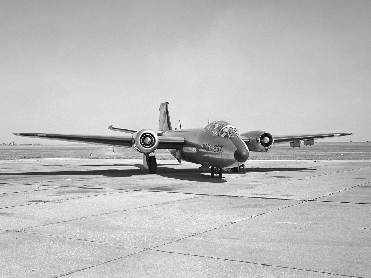 A Martin B-57B Canberra outfitted with a noise suppressor on its right engine at the National Aeronautics and Space Administration (NASA) Lewis Research Center. The aircraft was being prepared for the October 1966 Inspection of the center. The Inspection also marked Lewis’ twentieth anniversary. Lewis researchers had been studying engine noise for almost a decade, but the problem seemed to be increasing in the mid-1960s with heavier airline traffic and larger engines.     Researchers discovered early on that the majority of the noise did not emanate from the engine itself, but from the mixing of the hot exhaust gasses with the atmosphere. Attempts to reduce the turbulence using new exhaust nozzles were successful but often resulted in decreased engine performance. The researchers decided to try to lower the jet nozzle exit velocity without decreasing its thrust. The inlet mass air flow had to be increased to accomplish this.     The Lewis B-57B was powered by two Wright Aeronautical J65 turbojets. Lewis engineers modified the stators on the two engines to simulate the noise levels from more-modern turbofan engines. A noise suppressor was added to only one of the two engines, seen here on the left. The engines were run one at a time at power levels similar to landing while the aircraft sat on the Lewis hangar apron. A microphone and recording equipment was setup to capture the noise levels. The engine with the suppressor produced 13 fewer decibels than the standard engine.