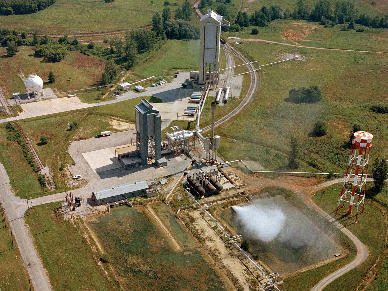 Operation of the High Energy Rocket Engine Research Facility (B-1), left, and Nuclear Rocket Dynamics and Control Facility (B-3) at the National Aeronautics and Space Administration’s (NASA) Plum Brook Station in Sandusky, Ohio. The test stands were constructed in the early 1960s to test full-scale liquid hydrogen fuel systems in simulated altitude conditions. Over the next decade each stand was used for two major series of liquid hydrogen rocket tests: the Nuclear Engine for Rocket Vehicle Application (NERVA) and the Centaur second-stage rocket program. The different components of these rocket engines could be studied under flight conditions and adjusted without having to fire the engine. Once the preliminary studies were complete, the entire engine could be fired in larger facilities.    The test stands were vertical towers with cryogenic fuel and steam ejector systems. B-1 was 135 feet tall, and B-3 was 210 feet tall. Each test stand had several levels, a test section, and ground floor shop areas. The test stands relied on an array of support buildings to conduct their tests, including a control building, steam exhaust system, and fuel storage and pumping facilities.    A large steam-powered altitude exhaust system reduced the pressure at the exhaust nozzle exit of each test stand. This allowed B-1 and B-3 to test turbopump performance in conditions that matched the altitudes of space.