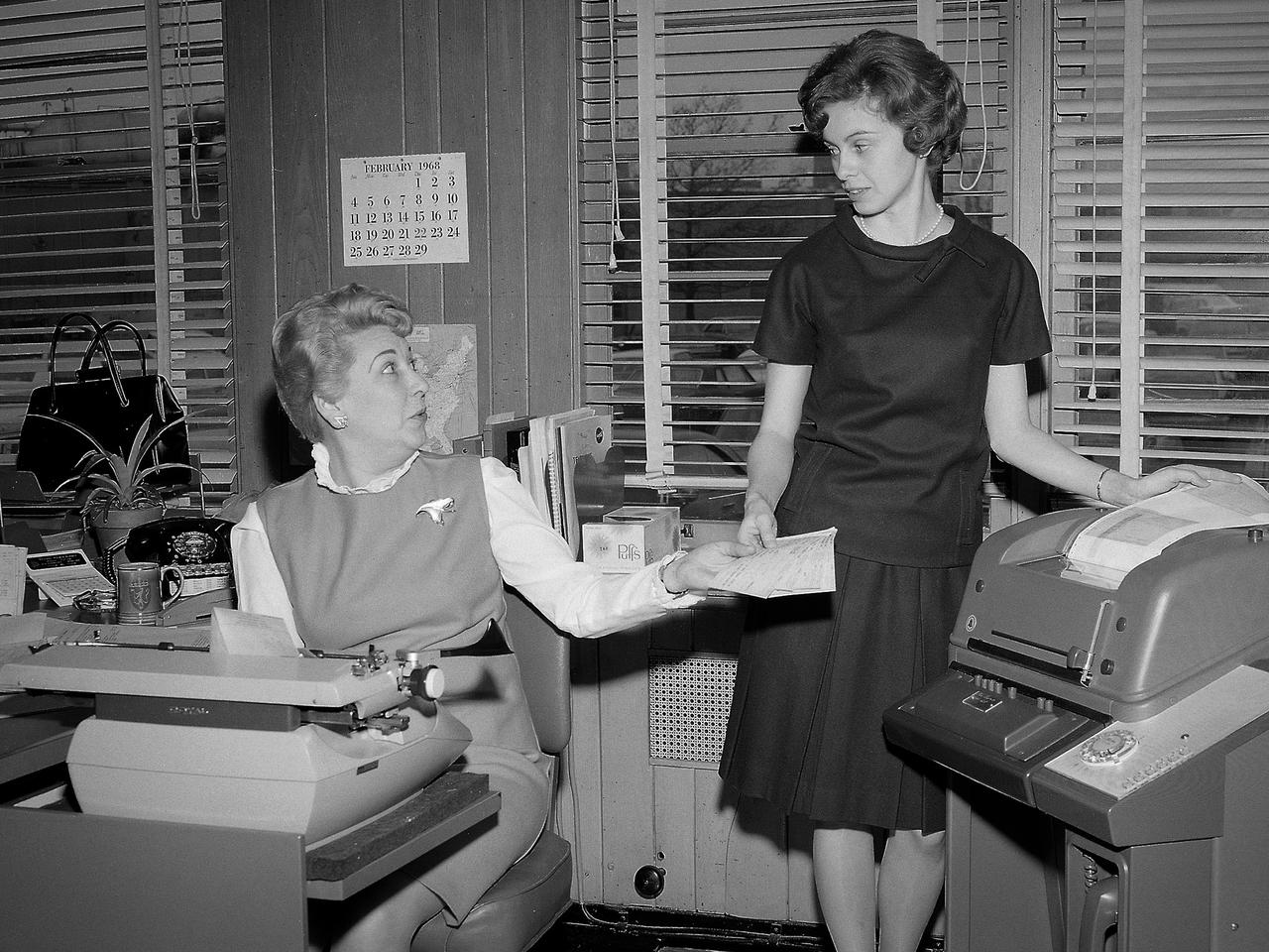 Peggy Heintz, left, receives an airline ticket from supervisor Judy Kuebeler in the Administrative Services Building at the National Aeronautics and Space Administration (NASA) Lewis Research Center. The center had recently purchased a teleticket machine that automatically printed airline tickets as directed by the airline’s computer system.    The Administrative Services Branch had 55 staff members performing a variety of roles. They served as telephone operators and set up communications with other centers. They operated the motor pool, handled all travel arrangements, prepared forms and work instructions, and planned offices. The staff was also responsible for records management and storage. It was reported that the staff processed 65 bags of incoming mail per day, which was said to be on par with a city of 15,000 to 20,000 people.