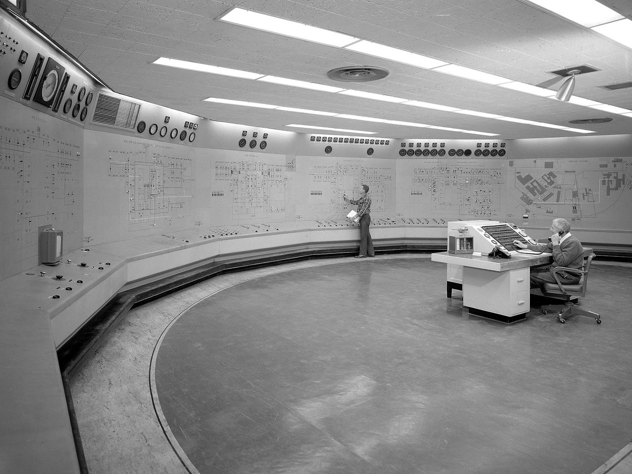Operators in the Engine Research Building’s Central Control Room at the National Aeronautics and Space Administration (NASA) Lewis Research Center. The massive 4.25-acre Engine Research Building contains dozens of test cells, test stands, and altitude chambers. A powerful a collection of compressors and exhausters located in the central portion of the basement provides process air and exhaust for these test areas. This system is connected to similar process air systems in the laboratory’s other large test facilities. The Central Control Room coordinates this activity and communicates with the local utilities.    The panels on the wall contain schematics with indicator lights and instrumentation for the atmospheric exhaust, altitude exhaust, refrigerated air, and process air systems. The process air equipment included twelve exhausters, four compressors, refrigeration system, cooling water, and an exhaust system. The operators in the control room kept in contact with engineers running the process air system and those conducting the tests in the test cells. The operators also coordinated with the local power companies to make sure enough electricity was available to operate the powerful compressors and exhausters.