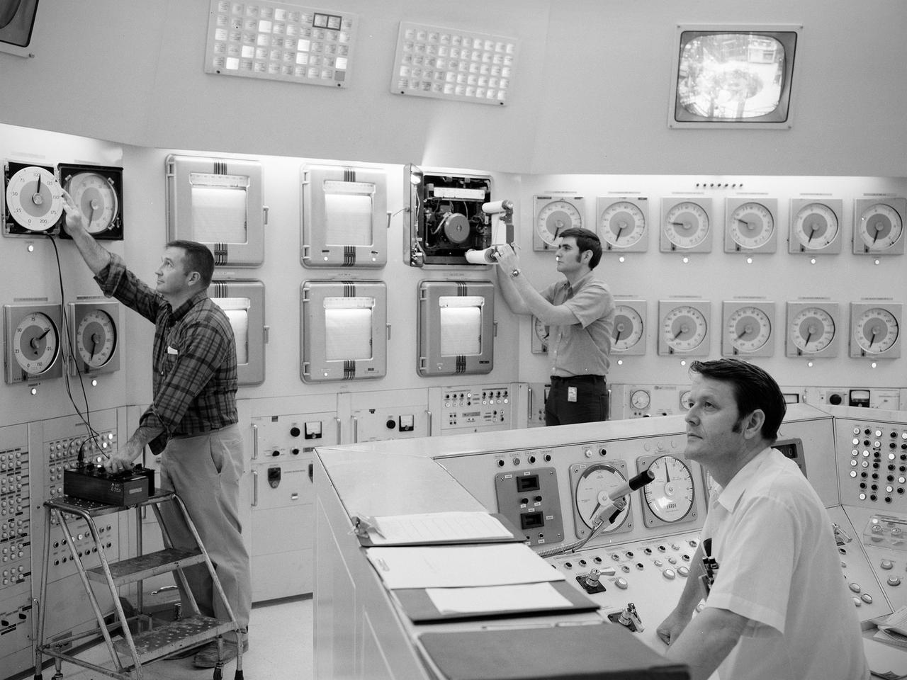 Donald Rhodes, left, and Clyde Greer, right, monitor the operation of the National Aeronautics and Space Administration’s (NASA) Plum Brook Reactor Facility from the control room. The 60-megawatt test reactor, NASA’s only reactor, was the eighth largest test reactor in the world. The facility was built by the Lewis Research Center in the late 1950s to study the effects of radiation on different materials that could be used to construct nuclear propulsion systems for aircraft or rockets. The reactor went critical for the first time in 1961. For the next two years, two operators were on duty 24 hours per day working on the fission process until the reactor reached its full-power level in 1963.    Reactor Operators were responsible for monitoring and controlling the reactor systems. Once the reactor was running under normal operating conditions, the work was relatively uneventful. Normally the reactor was kept at a designated power level within certain limits. Occasionally the operators had to increase the power for a certain test. The shift supervisor and several different people would get together and discuss the change before boosting the power.      All operators were required to maintain a Reactor Operator License from the Atomic Energy Commission. The license included six months of training, an eight-hour written exam, a four-hour walkaround, and testing on the reactor controls.