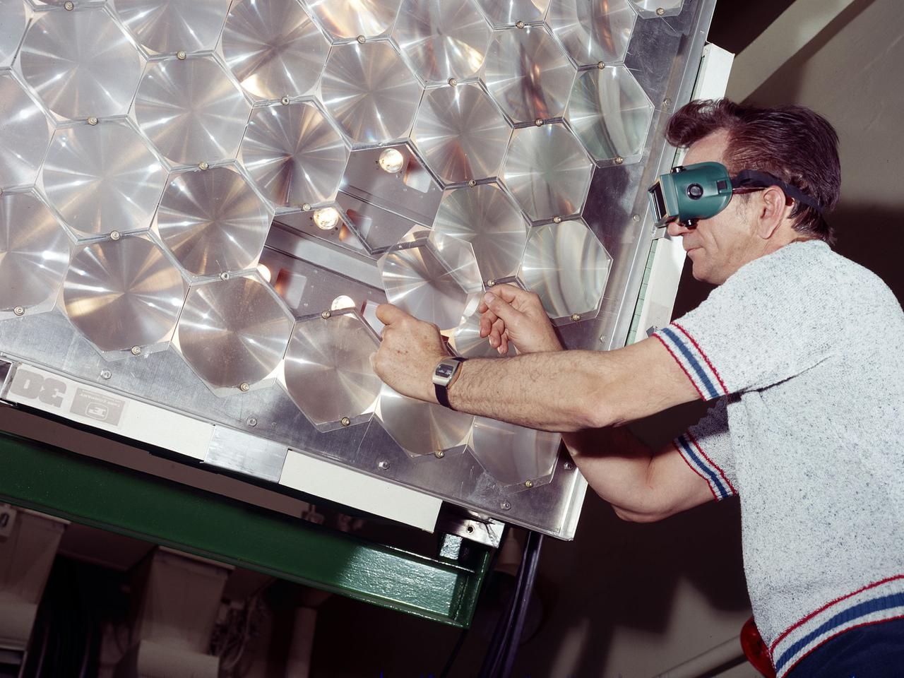 A NASA engineer installs a solar cell into a large array of solar cells.