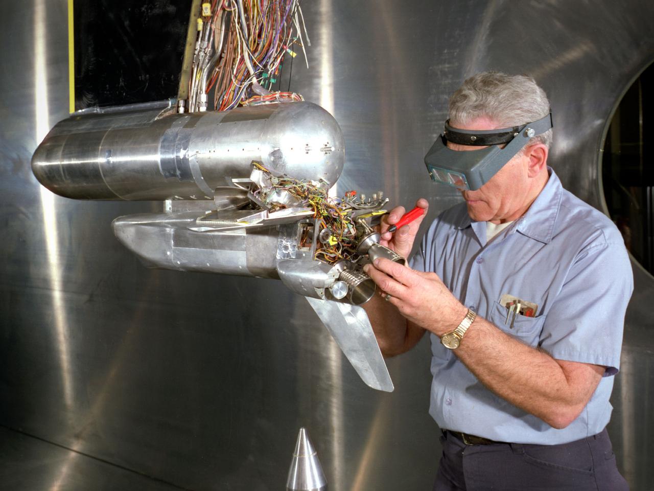 A technician prepares a 2.25 percent scale model of the space shuttle for a base heat study in the 10- by 10-Foot Supersonic Wind Tunnel at the National Aeronautics and Space Administration (NASA) Lewis Research Center. This space shuttle project, begun here in July 1976, was aimed at evaluating base heating and pressure prior to the Shuttle’s first lift-off scheduled for 1979. The space shuttle was expected to experience multifaceted heating and pressure distributions during the first and second stages of its launch. Engineers needed to understand these issues in order to design proper thermal protection.     The test’s specific objectives were to measure the heat transfer and pressure distributions around the orbiter’s external tank and solid rocket afterbody caused by rocket exhaust recirculation and impingement, to measure the heat transfer and pressure distributions caused by rocket exhaust-induced separation, and determine gas recovery temperatures using gas temperature probes and heated base components. The shuttle model’s main engines and solid rockets were first fired and then just the main engines to simulate a launch during the testing. Lewis researchers conducted 163 runs in the 10- by 10 during the test program.