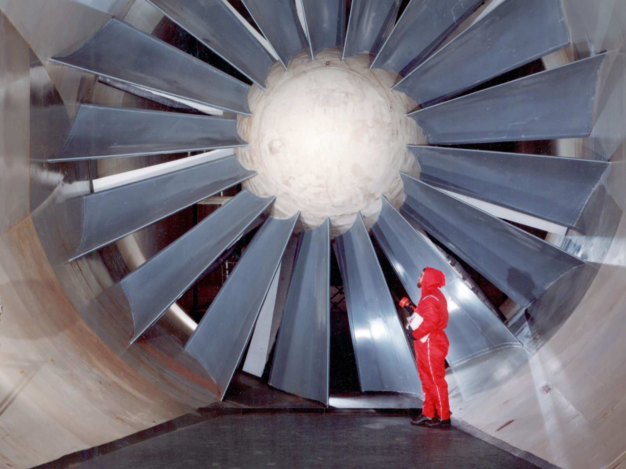 A person stands in front of a fan with large blades used in a wind tunnel to help illustrate our aeronautics leadership page.