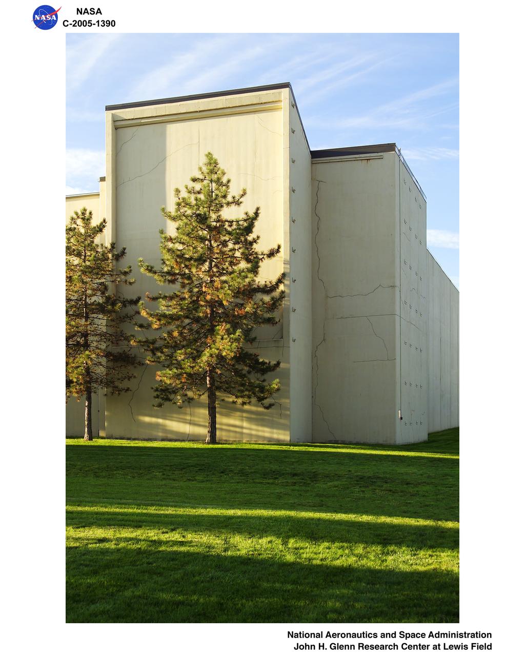North and West-facing facades of the 8x6 Supersonic Wind Tunnel in the early morning light. Caption:  In the early morning light, the strong geometric lines behind the soft pine trees caught the eye of a photographer at Glenn Research Center.  Behind the commanding facade lies the 8- by 6-Foot Supersonic Wind Tunnel (8x6 SWT), an atmospheric tunnel with perforated stainless steel walls that provide boundary control during transonic operations. It is NASA's only transonic propulsion wind tunnel.  http://facilities.grc.nasa.gov/8x6/8x6_quick.html