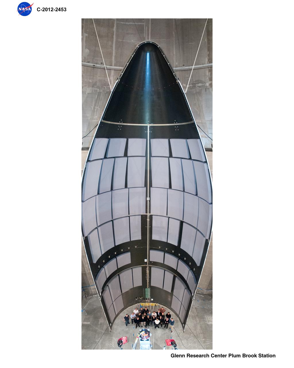 Space Power Facility at Plum Brook Station, RUAG Ariane 5 Shroud Separation Tests. GRC has the world's largest vacuum chamber in the world.  This world class facility is host to many space launch vehicle systems tests from customer's in this country and from around the world.  Shown here is the post test of a successful rocket shroud separation test.  The shroud, or top of a rocket, is jettisoned into two halves with explosive charges to allow the payload to be exposed  for deployment.  The payload, often time is a satellite, would be sitting atop the center white section shown in the middle of the photo.  This photo was taken from on top of the rocket holding the payload and both halves of the rocket shroud looking down at one of the shroud halves and the test crew at the bottom.