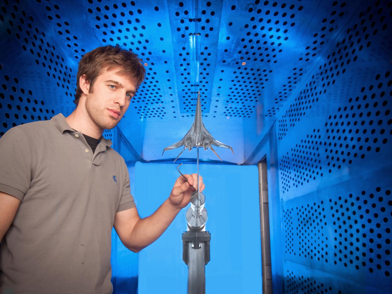 NASA Glenn engineer Gary Williamson with a small model of a future low-boom supersonic aircraft used for testing in the 8' x 6' Supersonic Wind Tunnel at NASA Glenn Research Center.