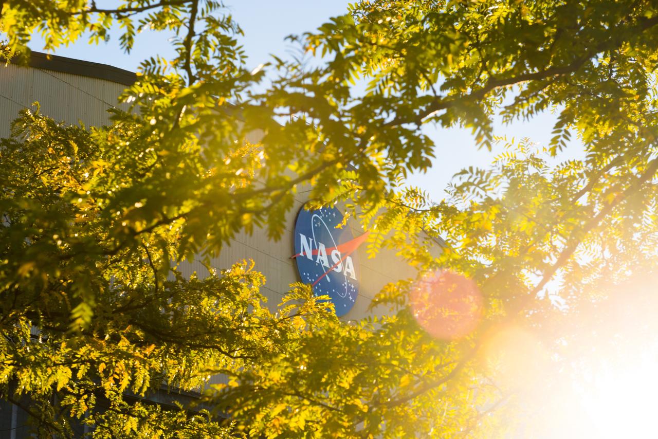 The NASA logo mounted on the south side of the Hangar at Glenn Research Center as seen through foliage.