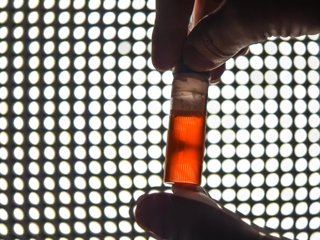 Ground testing for the first confocal Light Microscopy Microscope (LMM)  Experiment. Procter and Gamble is working with NASA Glenn scientists to prepare for a study that examines product stabilizers in a microgravity environment. The particles in the tube glow orange because they have been fluorescently tagged with a dye that reacts to green laser lights to allow construction of a 3D image point by point. The experiment, which will be sent to the ISS later this year, will help P&G develop improved product stabilizers to extend shelf life and develop more environmentally friendly packaging.