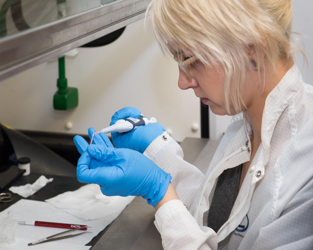 Deena Dombrosky (Zin Technologies Engineer) is shown here filling a Procter & Gamble (P & G) sample that will be used in ground-testing as NASA prepares for their experiment on the International Space Station (ISS).  The sample particles are the size of the wavelength of light and they are dyed orange/pink to glow when illuminated with the laser light enabling a confocal microscope to produce 3D images.  The P & G experiment will improve product stabilizers that extend product shelf life.  This has the added advantage of leading to more compact environmentally friendly containers.