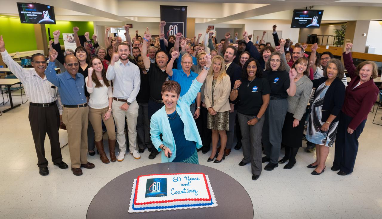 The Glenn Research Center Deputy Director, Dr. Marla Perez-Davis, cuts the ceremonial cake while employees cheer the NASA 60th Anniversary at the Employee Culminatiing Event.