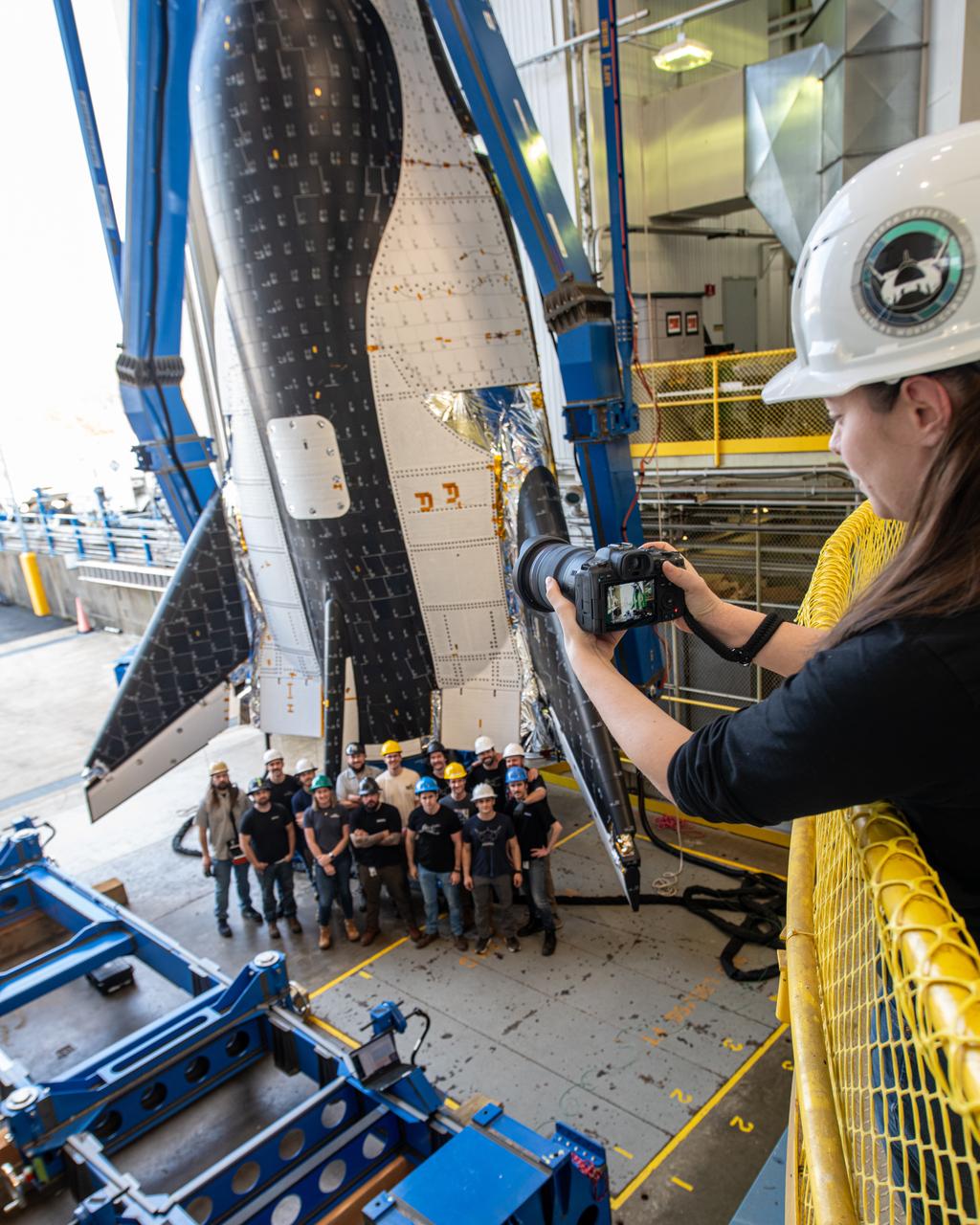 Sierra Space photographer, Shay Saldana is photographed taking a group photo of the crew just before the critical lift of Dream Chaser into the chamber at ISP (In Space Propulsion) NASA GRC-ATF.  Once lifted and lowered into the test chamber, it will be exposed to the harsh cold conditions of space for extended periods of time
