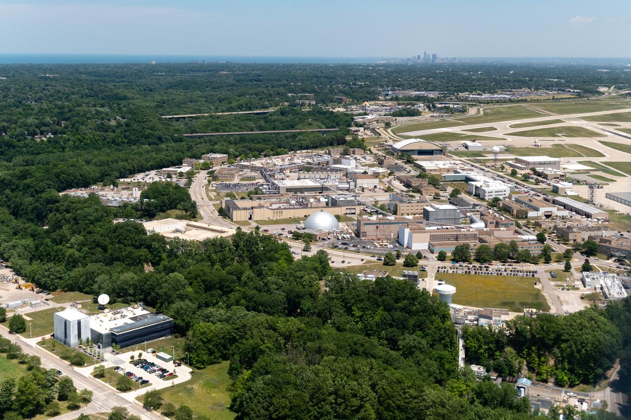 Aerial Photograph of Glenn Research Center With Downtown Cleveland in the Distance taken from the PC-12 on June 13, 2024.  A team at NASA’s Glenn Research Center in Cleveland streamed 4K video footage from an aircraft to the International Space Station and back for the first time using optical, or laser, communications. The feat was part of a series of tests on new technology that could provide live video coverage of astronauts on the Moon during the Artemis missions.  Working with the Air Force Research Laboratory and NASA’s Small Business Innovation Research program, Glenn engineers temporarily installed a portable laser terminal on the belly of a Pilatus PC-12 aircraft. They then flew over Lake Erie sending data from the aircraft to an optical ground station in Cleveland. From there, it was sent over an Earth-based network to NASA’s White Sands Test Facility in Las Cruces, New Mexico, where scientists used infrared light signals to send the data. Photo Credit: (NASA/Sara Lowthian-Hanna)