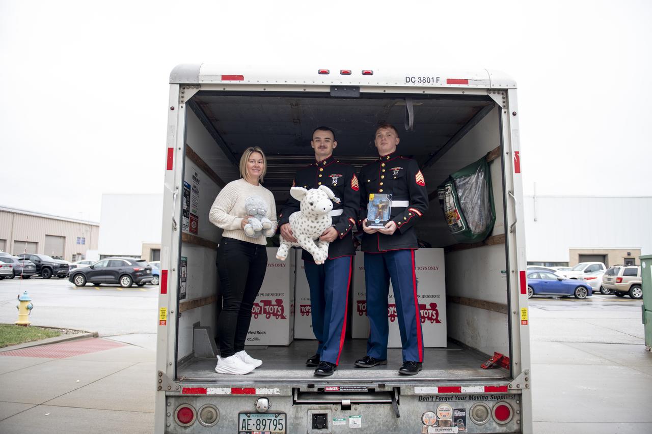 The US Marine Corps Reserve Collected Toy Donations for the 2024 Holiday Season. Samantha Yousef  and two members of the Marines poses with the collections. Photo Credit: (NASA/Sara Lowthian-Hanna)
