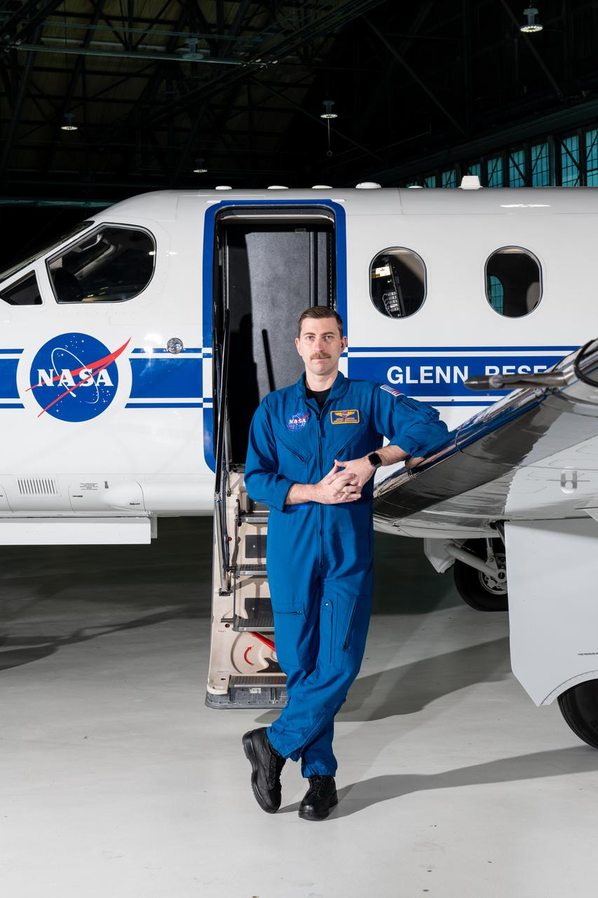 Jeremy Johnson, a research pilot and aviation safety officer, poses in front of a PC-12 aircraft inside the hangar at NASA’s Glenn Research Center in Cleveland on Thursday, April 17, 2025. Johnson flies NASA planes to support important scientific research and testing, working with researchers to plan and carry out flights that will get them the data they need while ensuring safety.