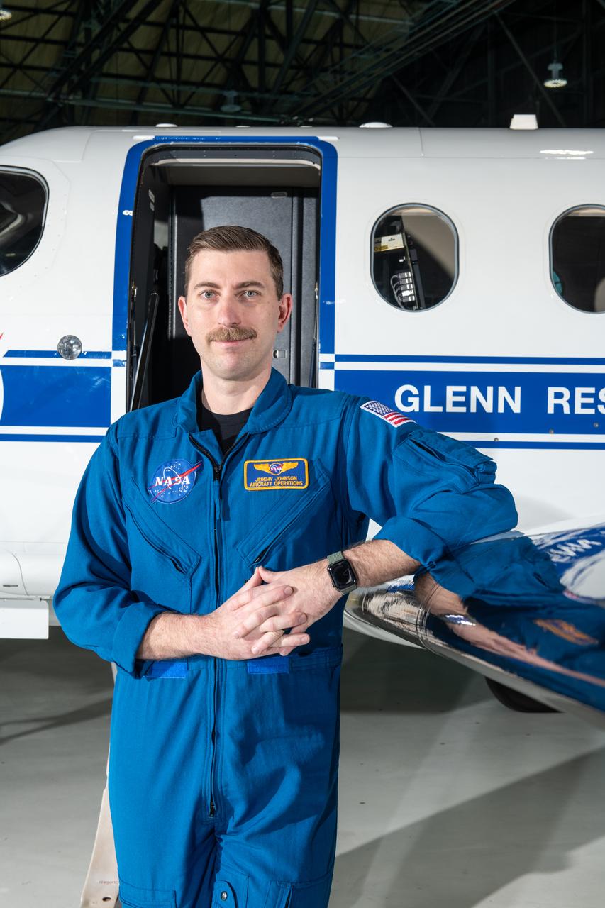 Jeremy Johnson, a research pilot and aviation safety officer, poses in front of a PC-12 aircraft inside the hangar at NASA’s Glenn Research Center in Cleveland on Thursday, April 17, 2025. Johnson flies NASA planes to support important scientific research and testing, working with researchers to plan and carry out flights that will get them the data they need while ensuring safety.