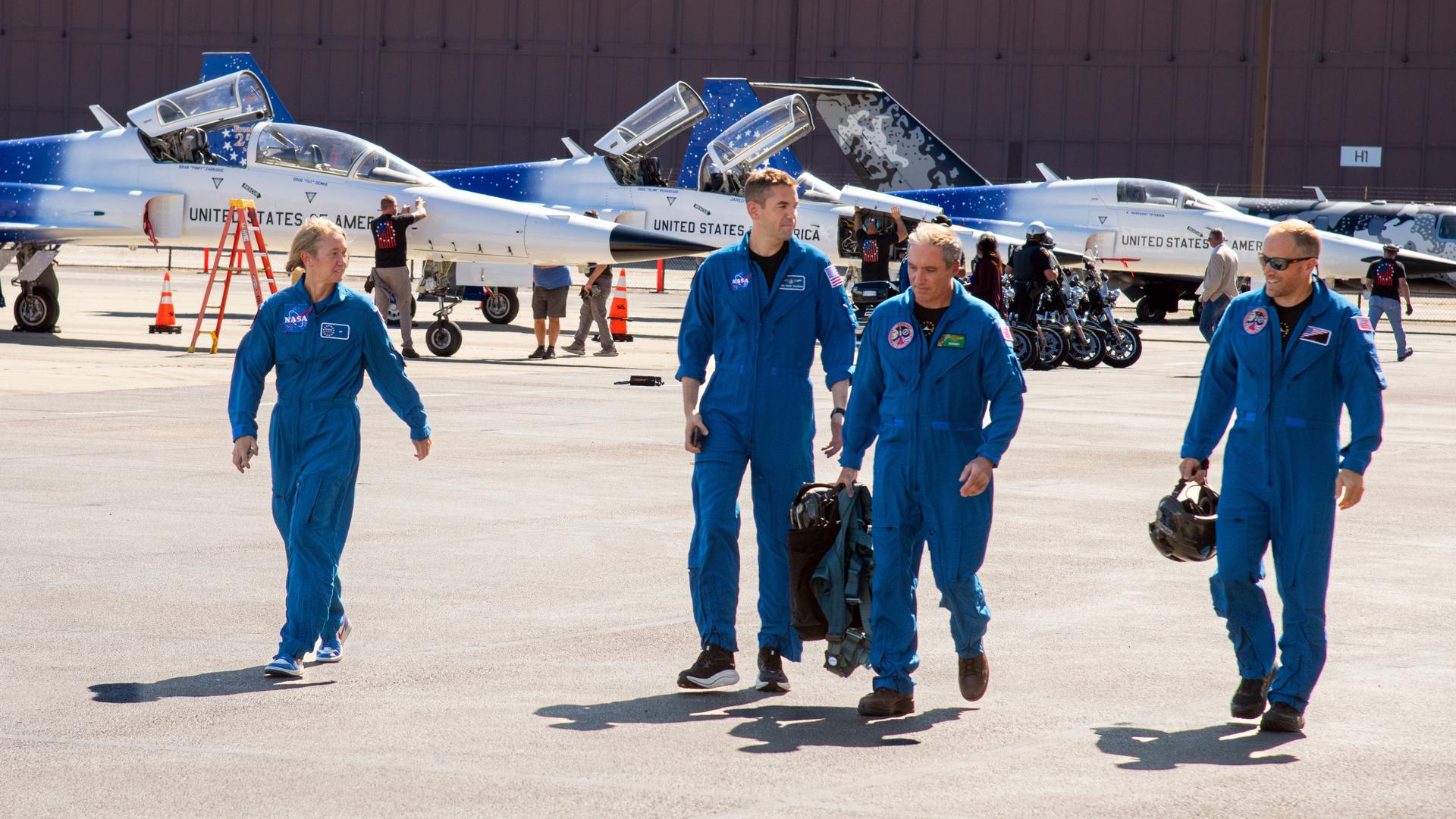 NASA Administrator Jared Isaacman and two GRC employees’ riders fly over the Cleveland Browns football game start.  Heather Brown walks with the pilots Isaacman, "Handy" and "Tut" after their flight.